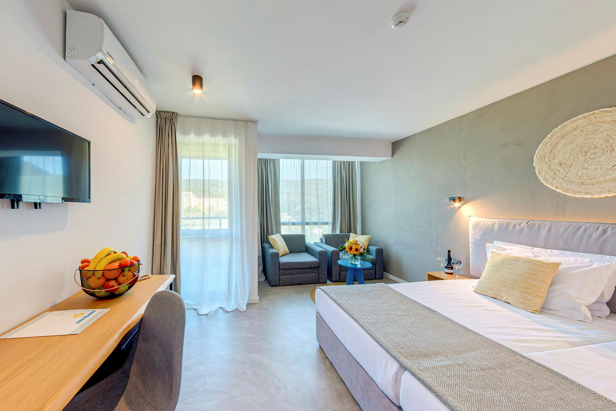 Modernt hotellrum med säng, skrivbord, två fåtöljer och fönster. (AI-genererad text)