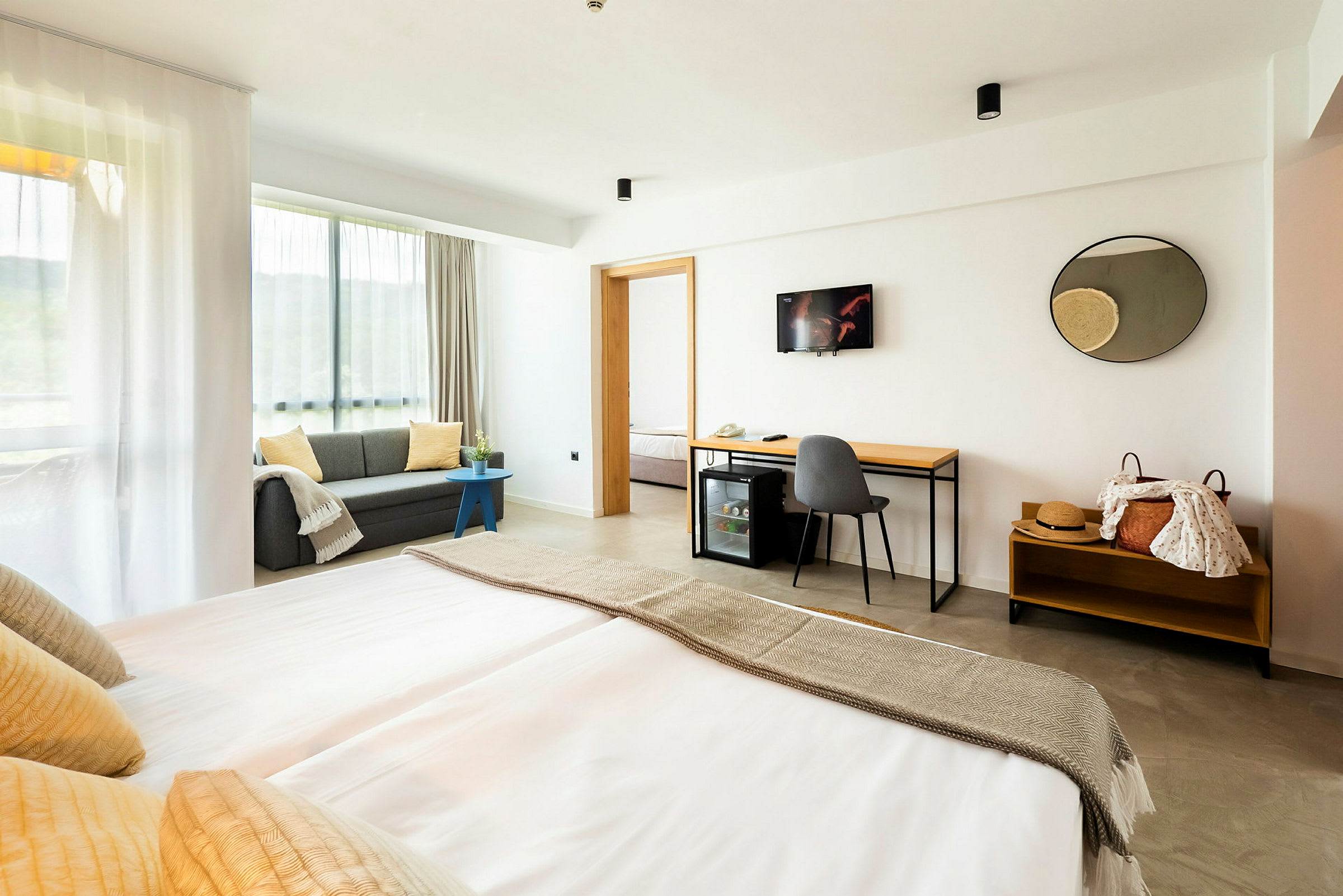 Modernt hotellrum med dubbelsäng, soffa och skrivbord. (AI-genererad text)