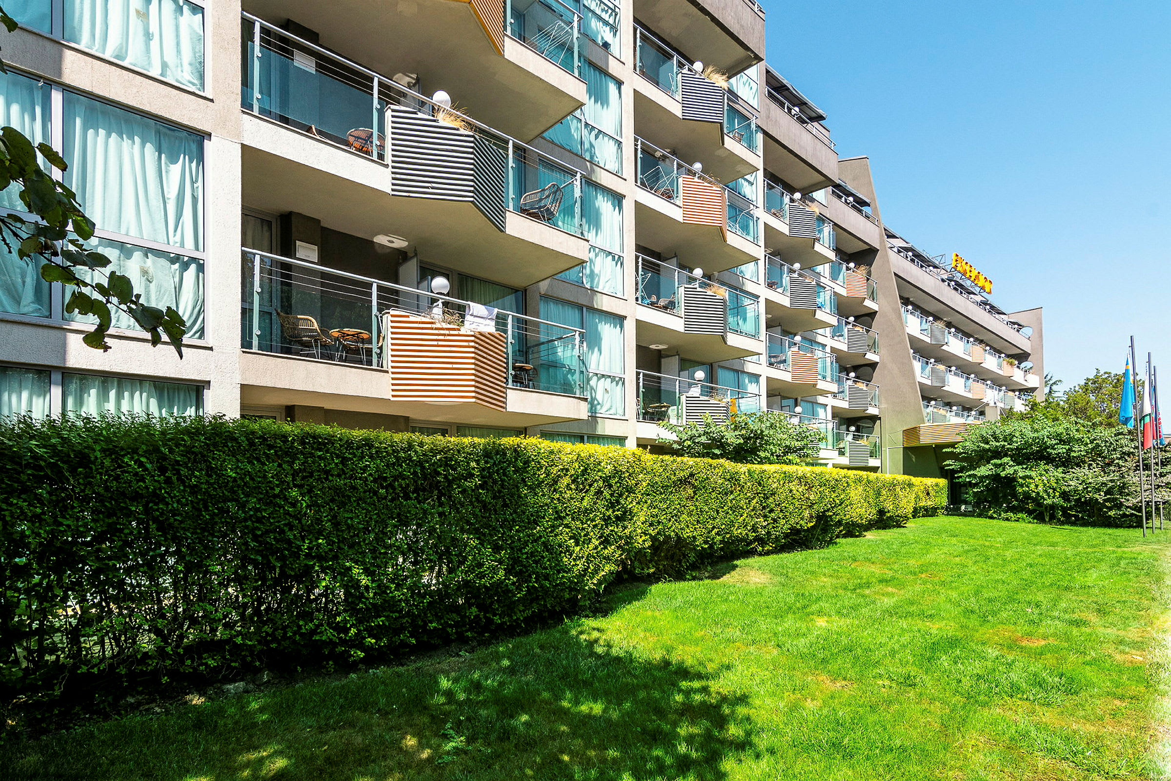 Bild av en hotellbyggnad med flera balkonger och omgivande grönska. (AI-genererad text)