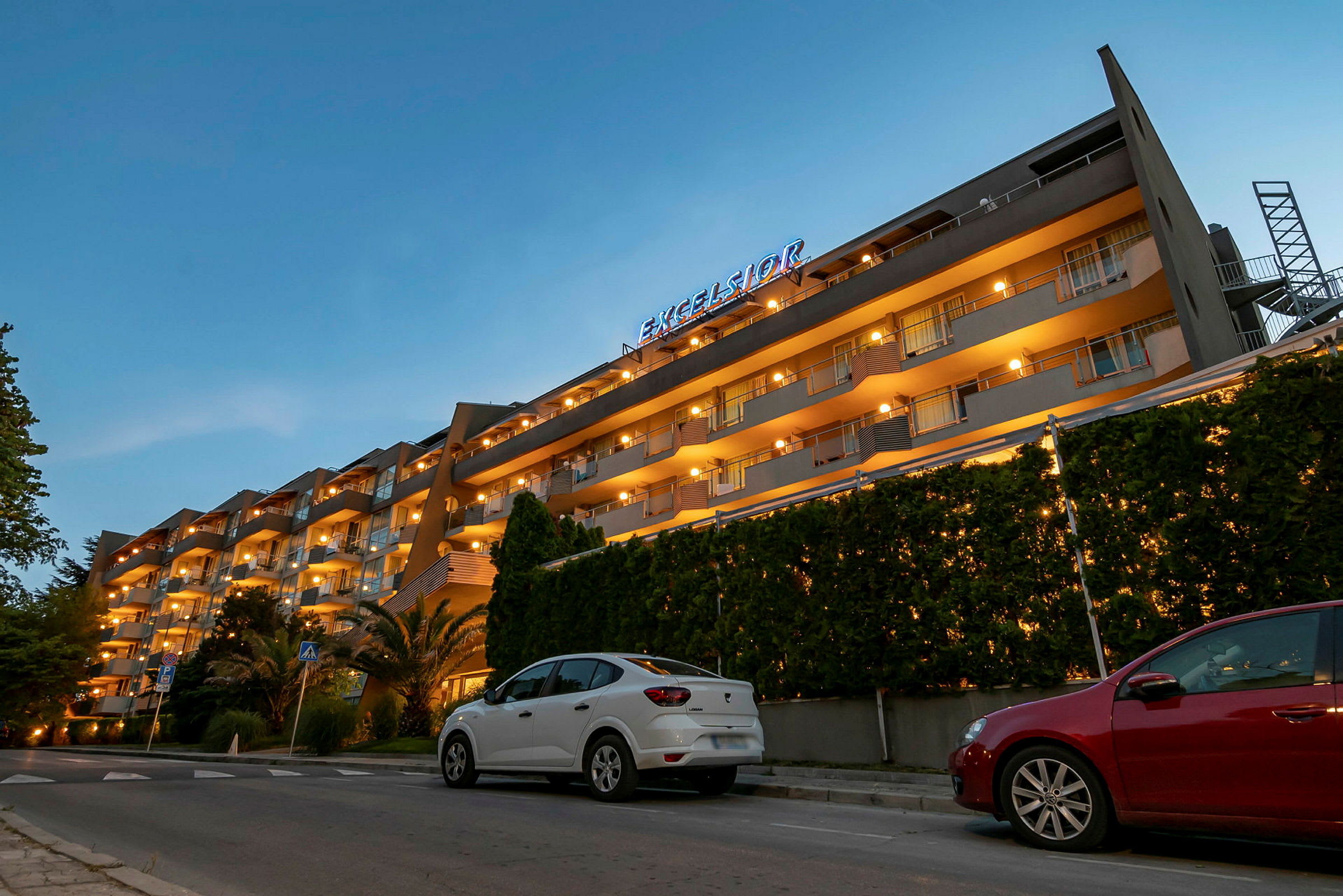 Ett hotell med flera våningar och upplysta balkonger på kvällen. (AI-genererad text)