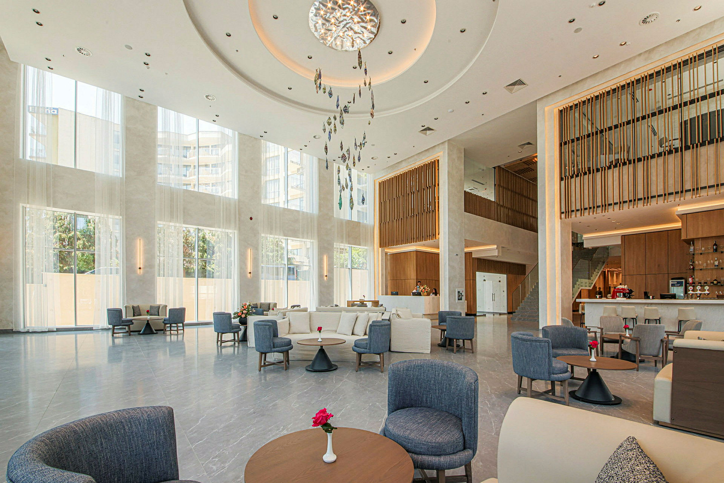 Bild på en ljus hotellobby med stora fönster, modern inredning och sittgrupper. (AI-genererad text)