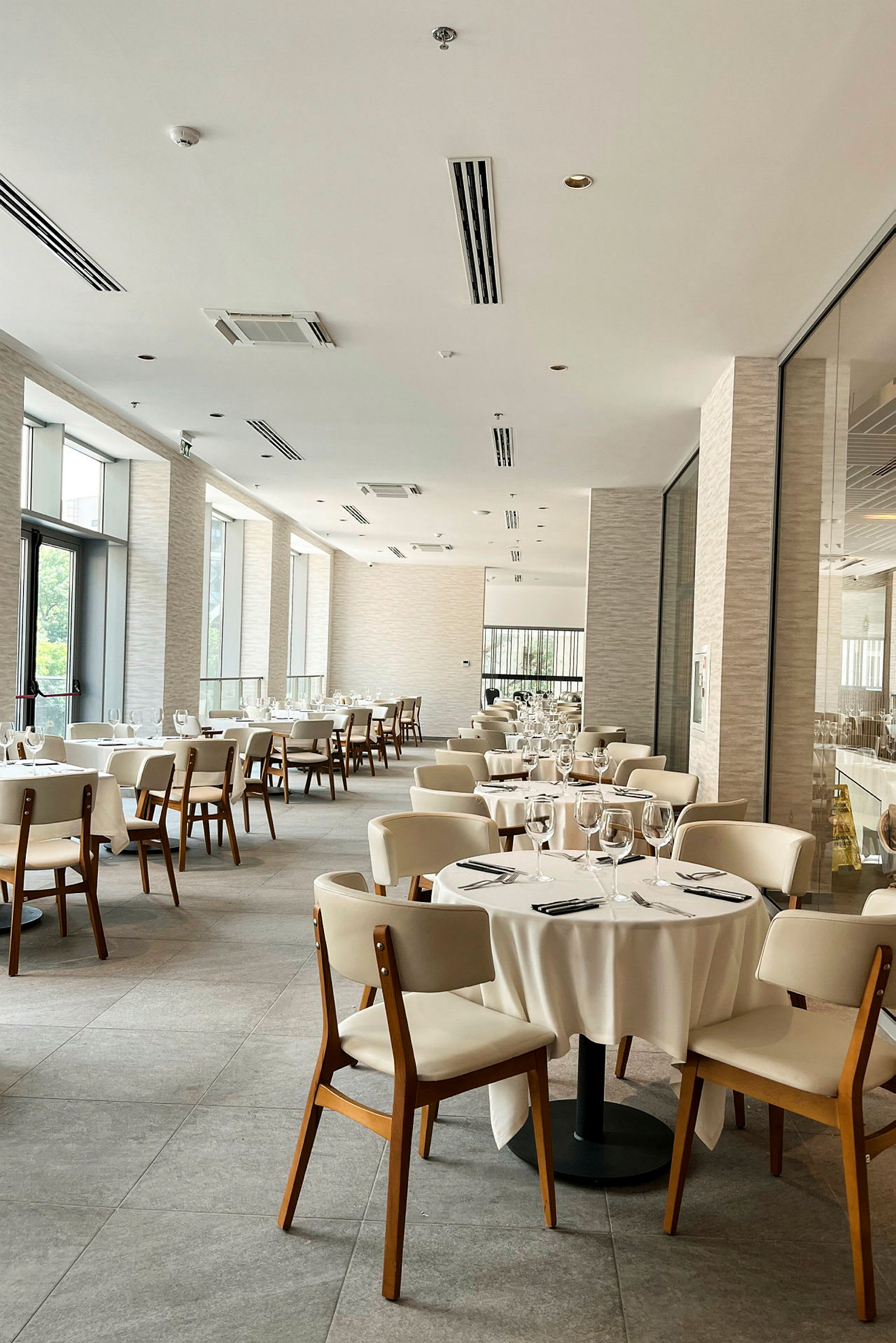 En elegant restaurang med vita dukar och dukade bord på ett ljust golv. (AI-genererad text)