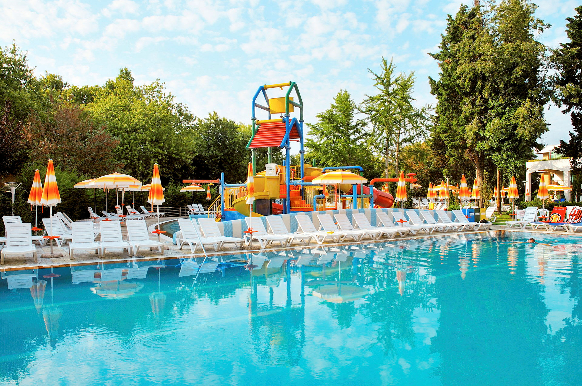 Pool med solstolar och lekplats i bakgrunden. (AI-genererad text)