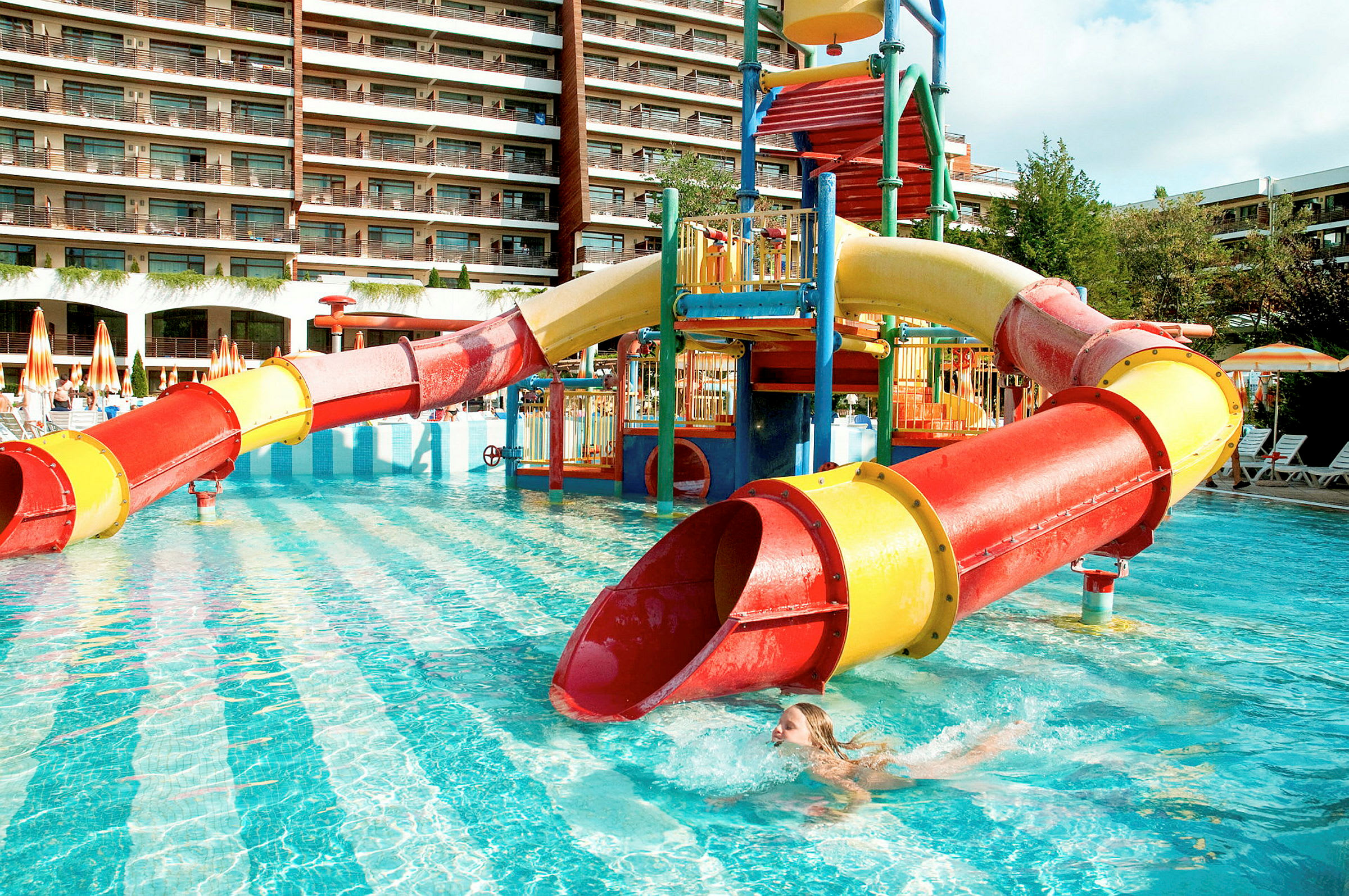 Vattenrutschkana vid poolområde med hotell i bakgrunden. (AI-genererad text)