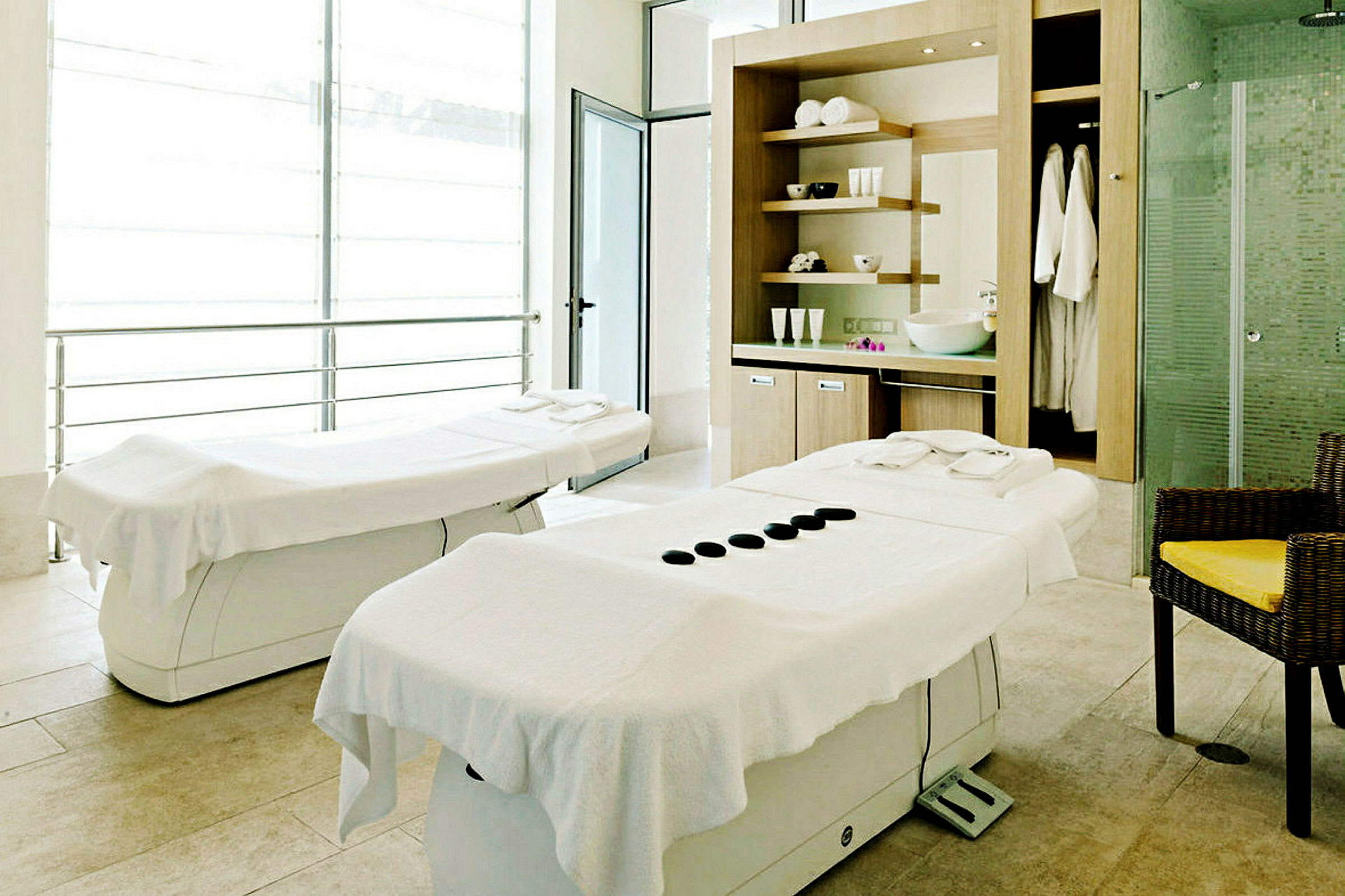 Två massagebänkar i ett ljust rum med spa-inredning. (AI-genererad text)