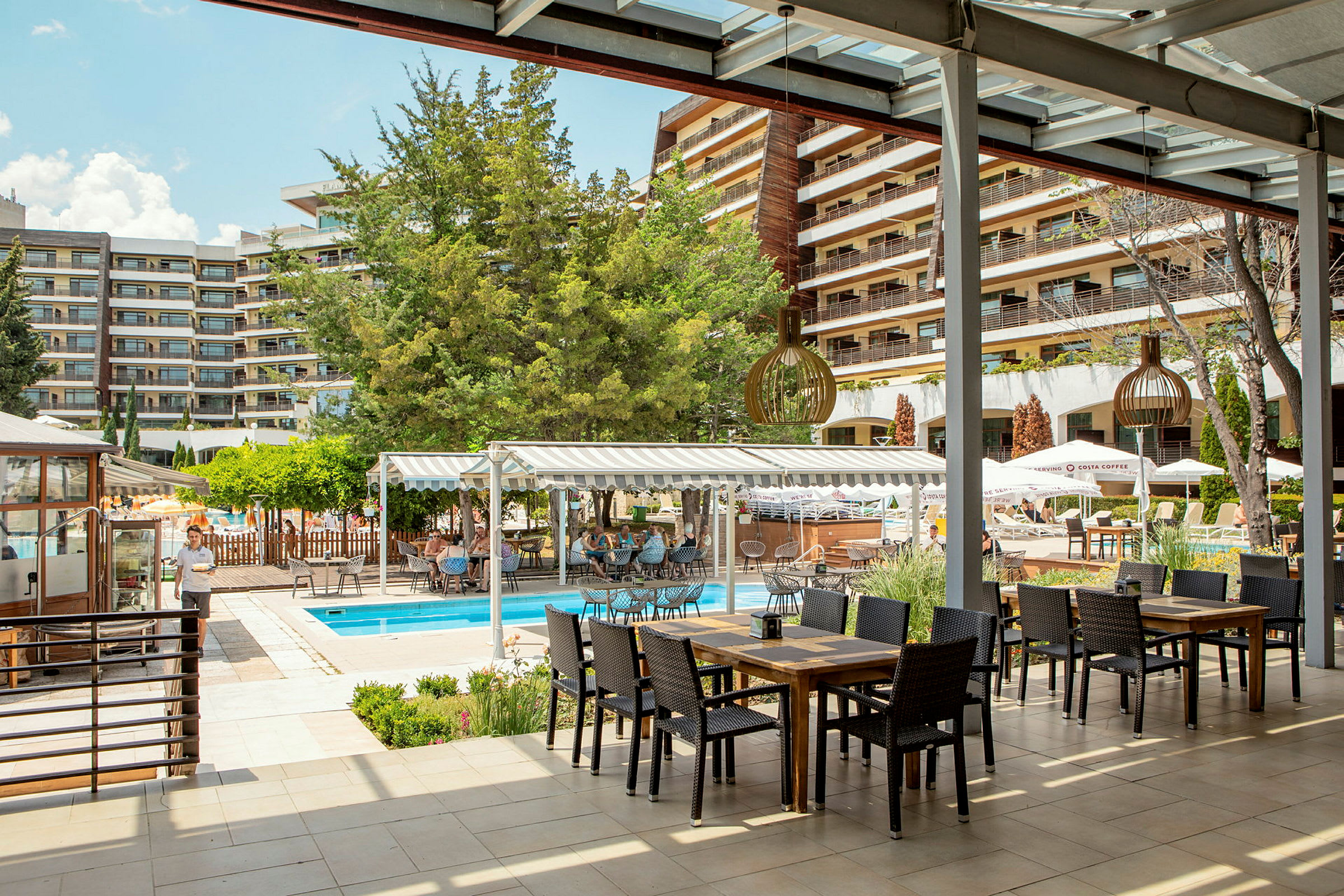 Utomhusområde vid hotell med en pool och sittplatser under tak. (AI-genererad text)