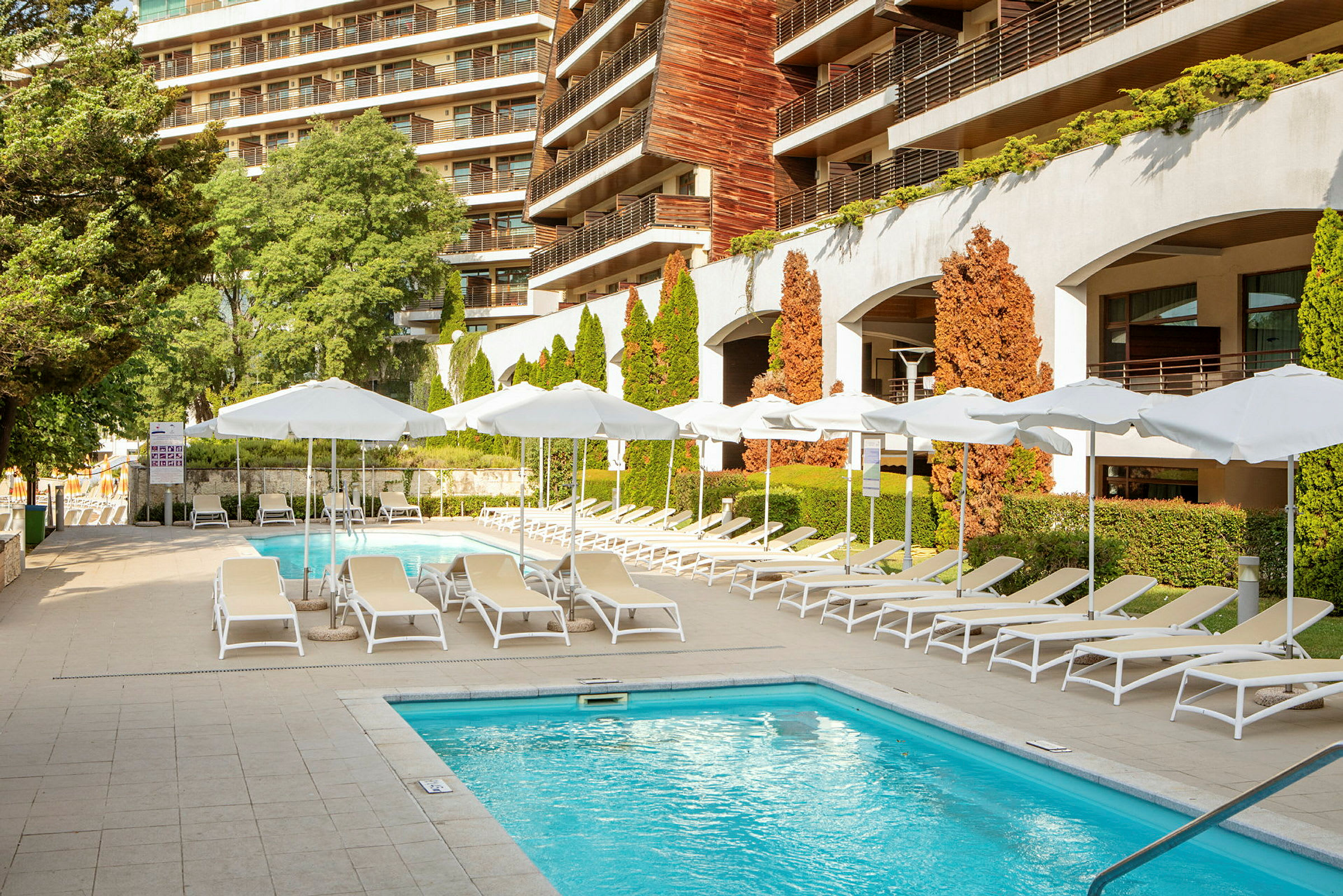 Utomhuspool med solstolar och parasoller vid ett hotell. (AI-genererad text)