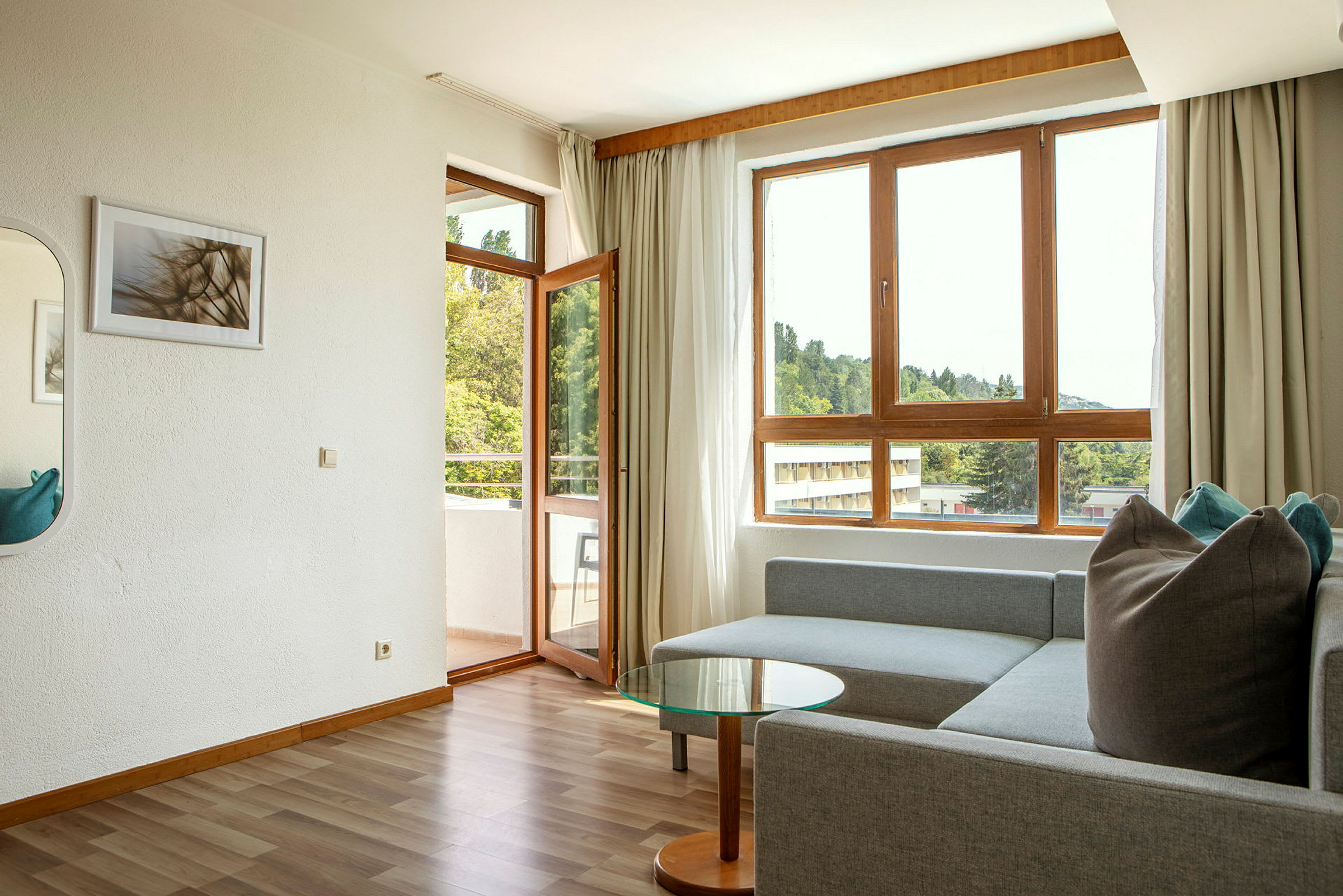 Modernt vardagsrum med soffa, glasbord och stora fönster med utsikt. (AI-genererad text)