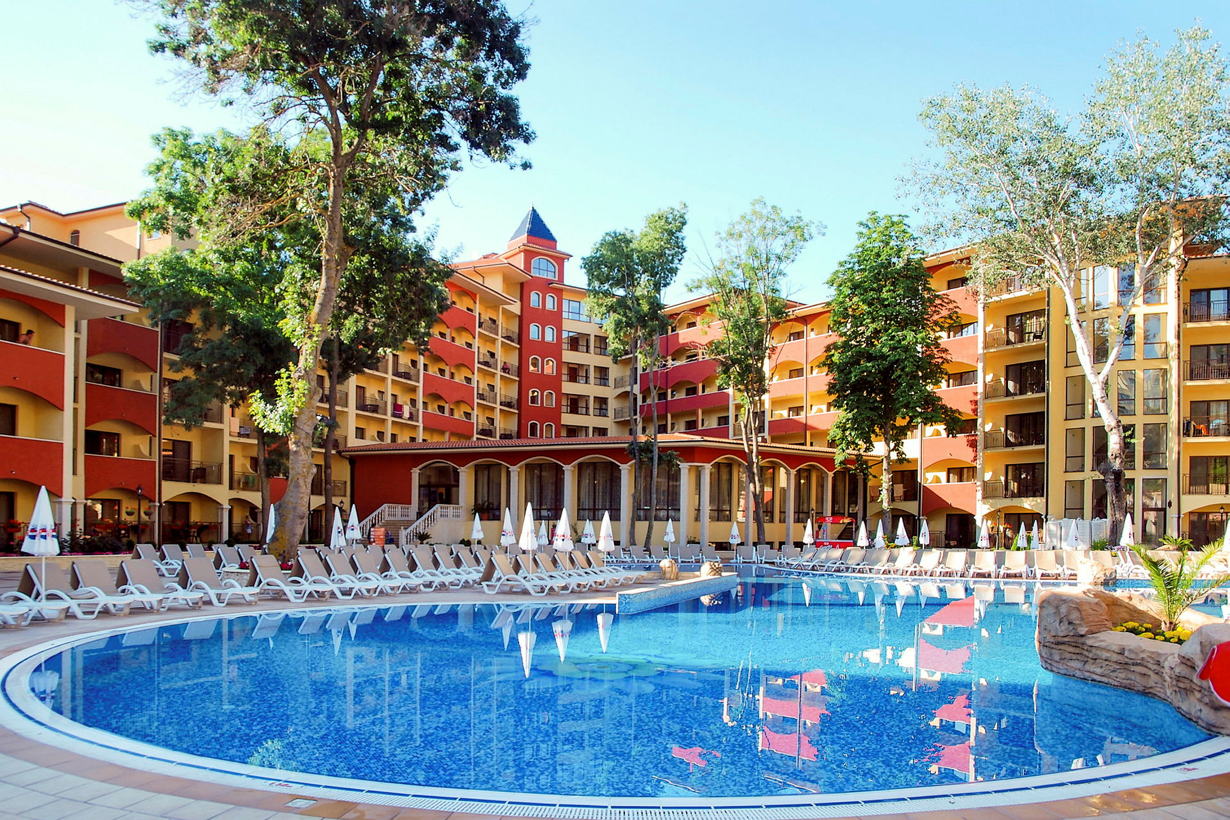 Bild av ett hotell med en stor pool och solstolar utomhus. (AI-genererad text)