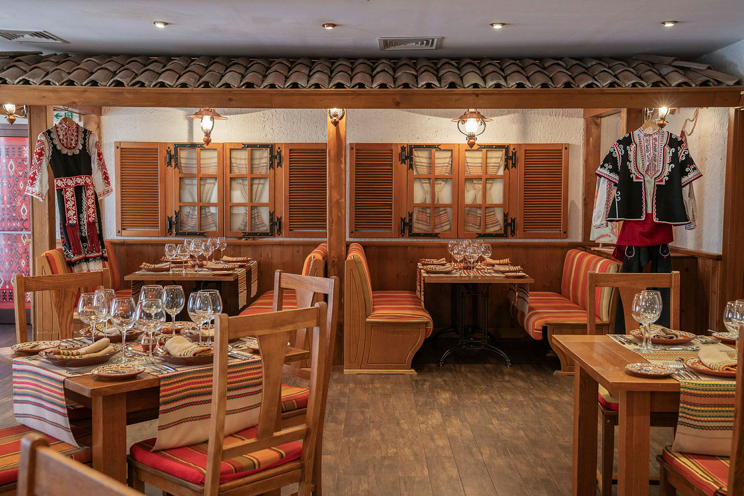 Bild av en restaurang med traditionella träbord, färgade sittdynor och folkloristiska kläder som dekoration. (AI-genererad text)