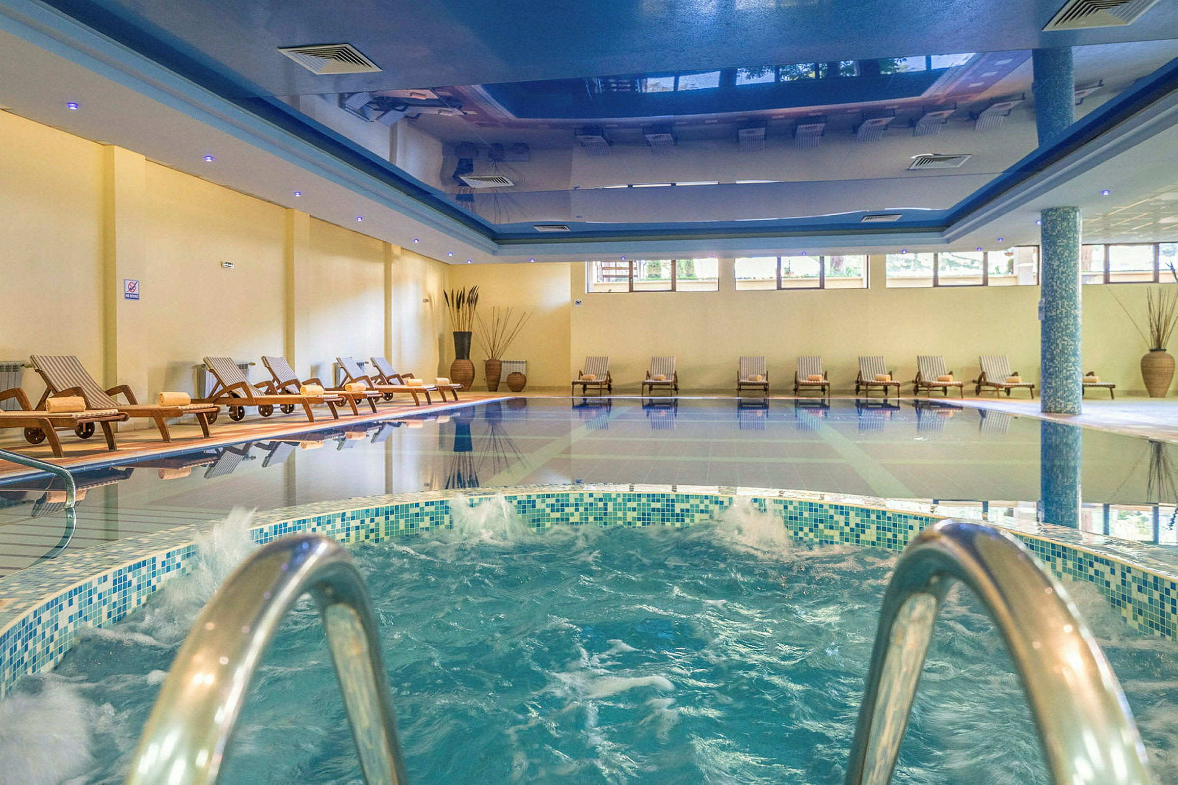 Inomhuspoolområde med bubbelpool och solstolar. (AI-genererad text)