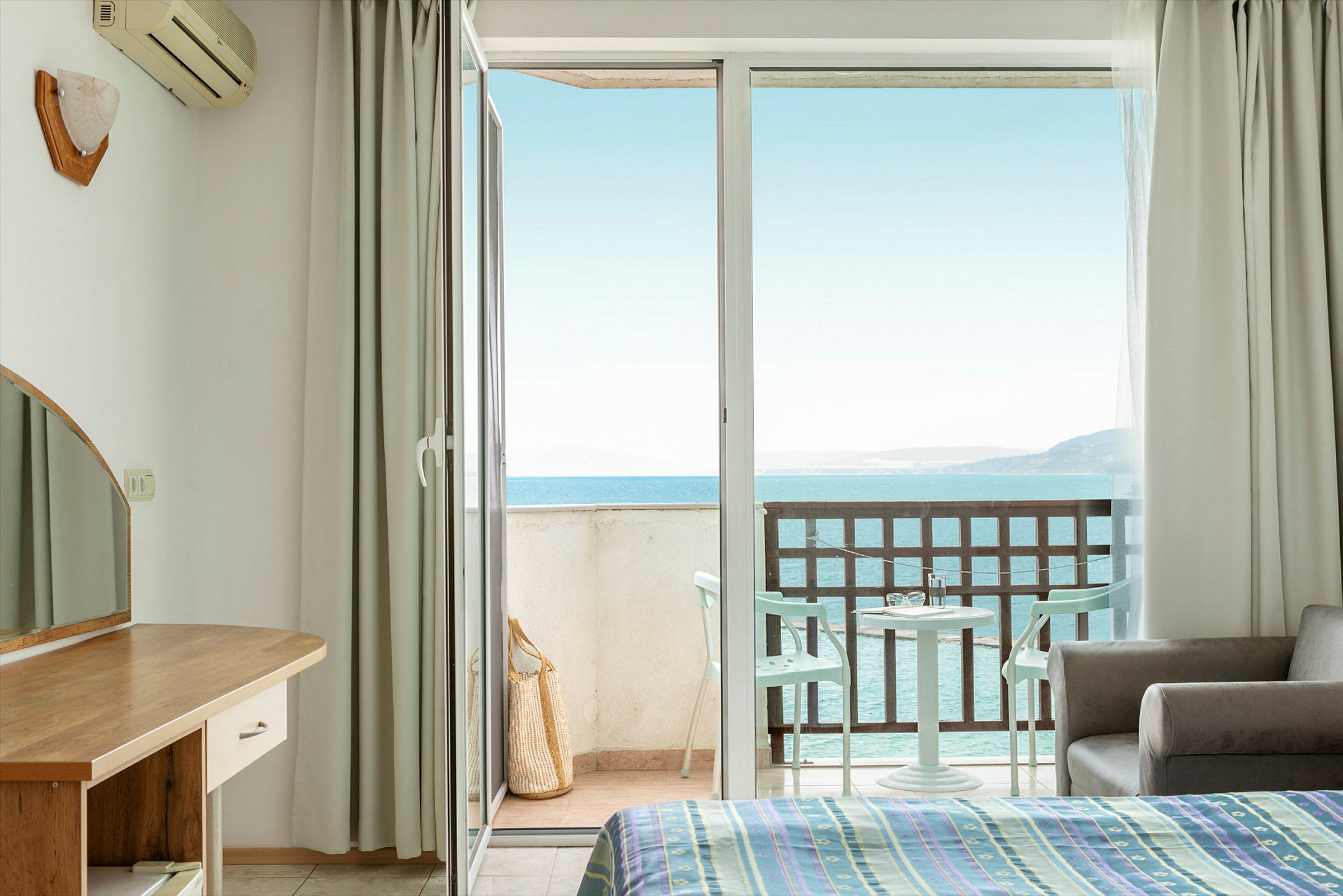 Hotelrum med öppen balkongdörr och havsutsikt. (AI-genererad text)