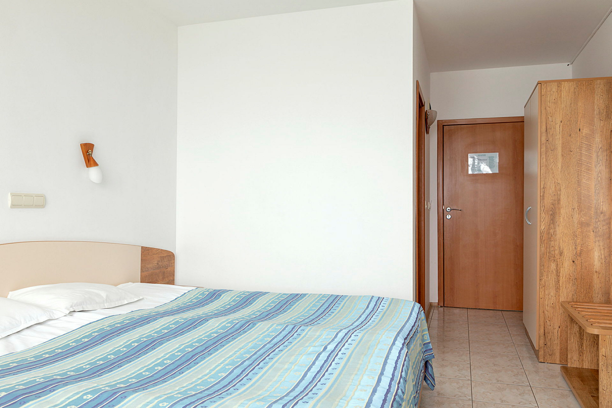 Hotellrum med säng, garderob och dörröppning. (AI-genererad text)