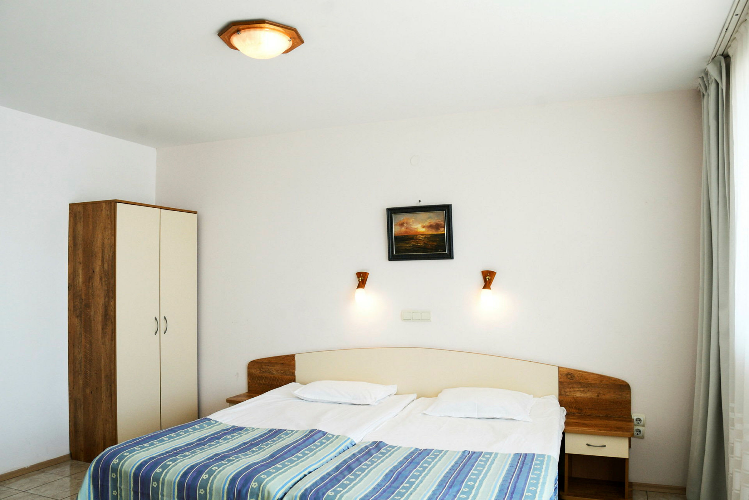 Ett hotellrum med en dubbelsäng, nattduksbord och garderob. (AI-genererad text)