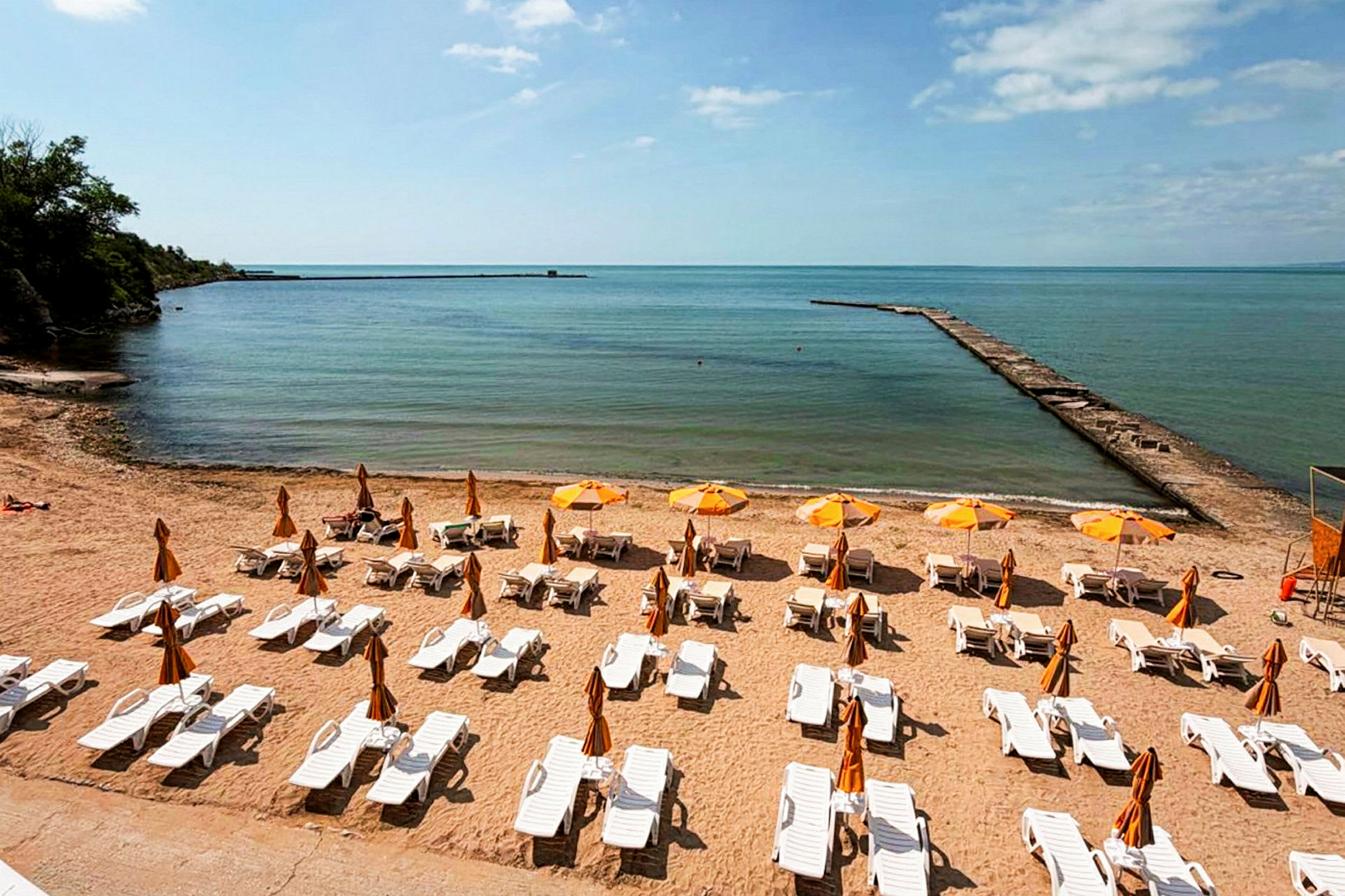 En sandstrand med solstolar och parasoller som vetter mot havet. (AI-genererad text)