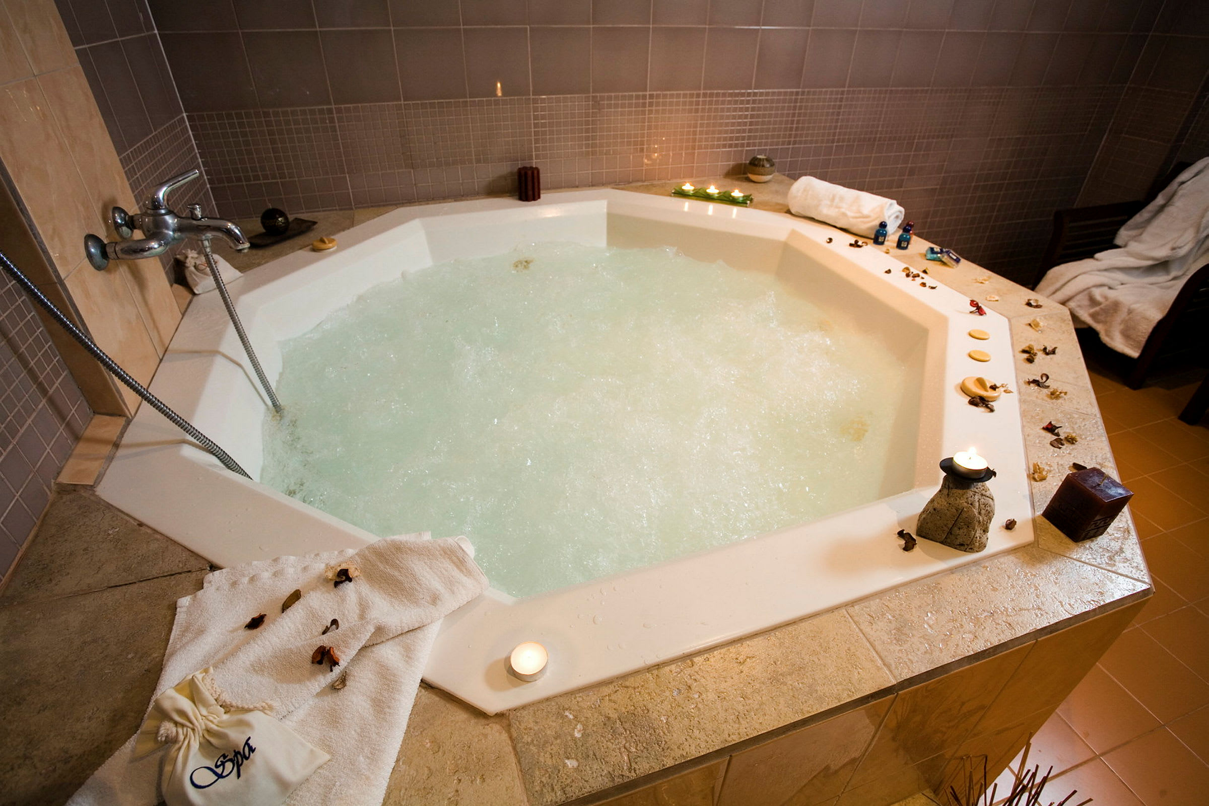 Inomhusjacuzzi med bubblande vatten, omgiven av dekor och levande ljus. (AI-genererad text)