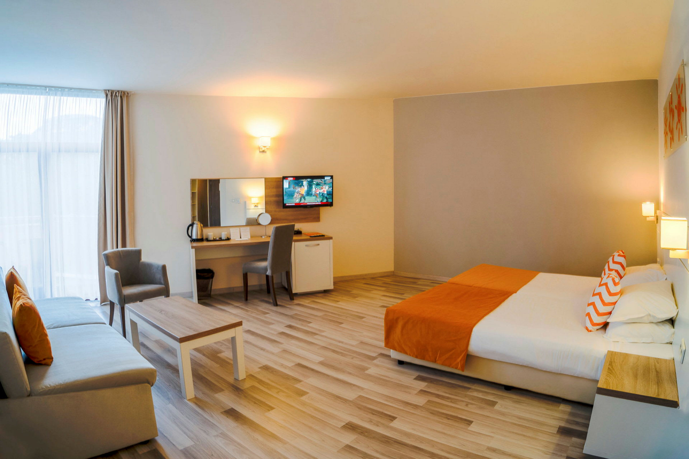 Bild av ett rymligt hotellrum med en stor säng, soffa, bord och arbetsområde, inrett i neutrala och orange toner. (AI-genererad text)