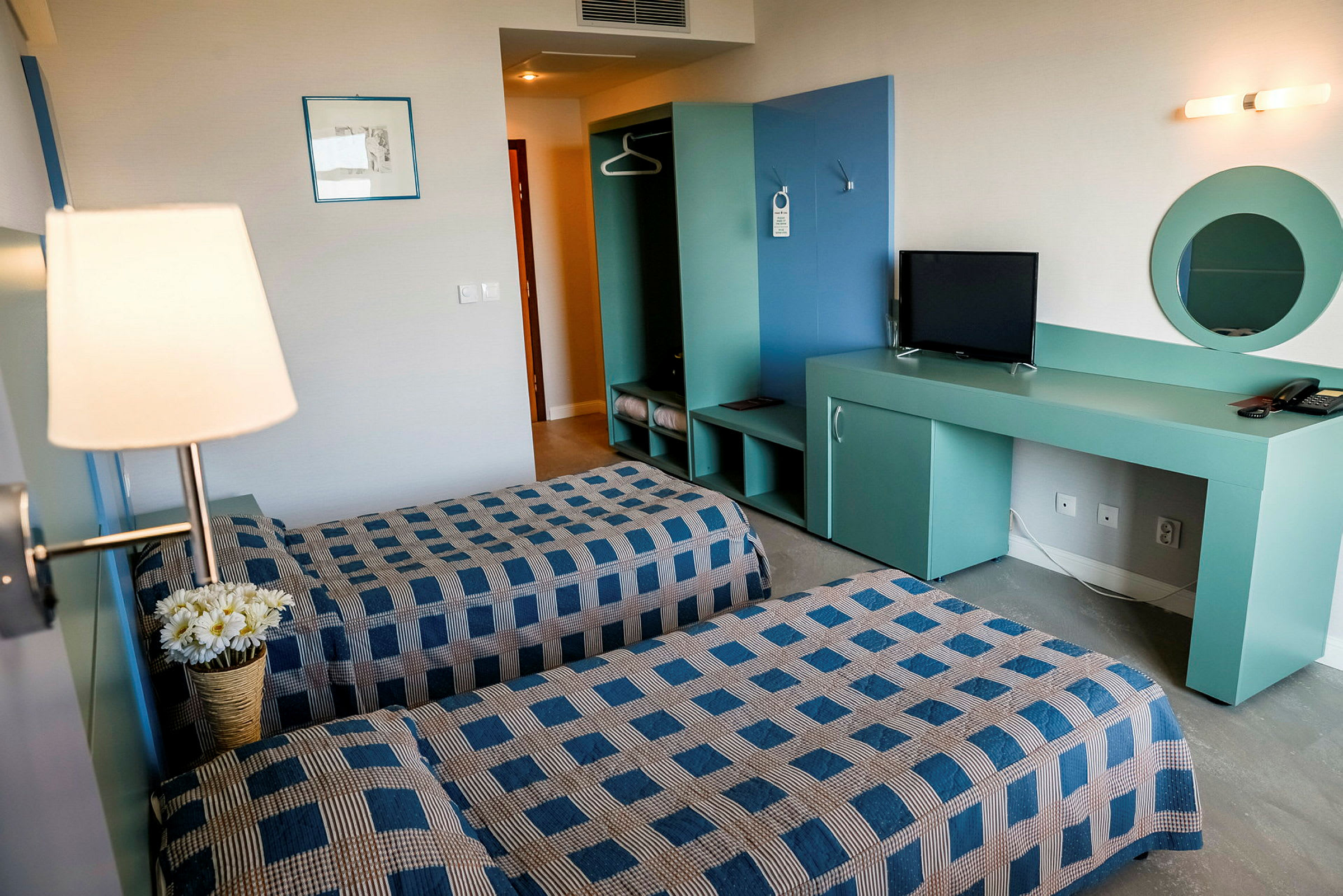 Ett hotellrum med två enkelsängar, tv, och garderob. (AI-genererad text)