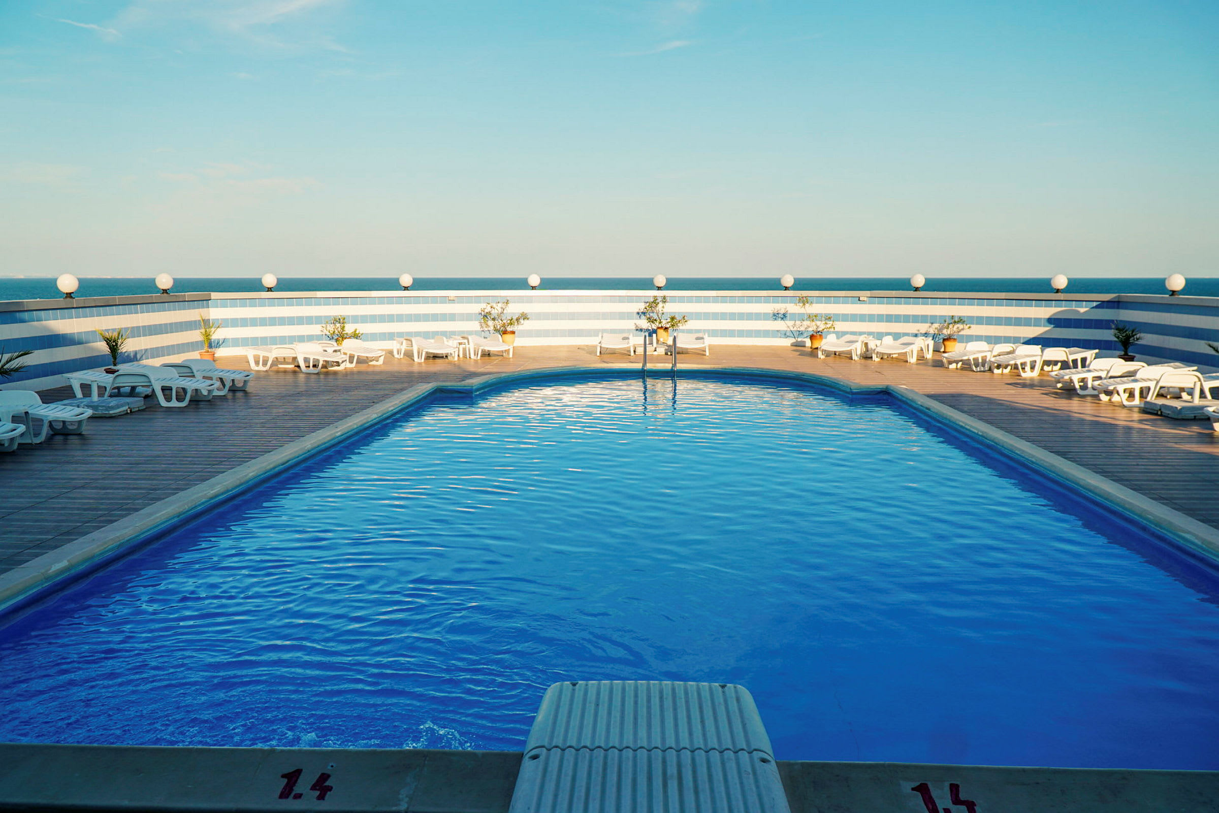 Pool med solstolar och blå himmel. (AI-genererad text)