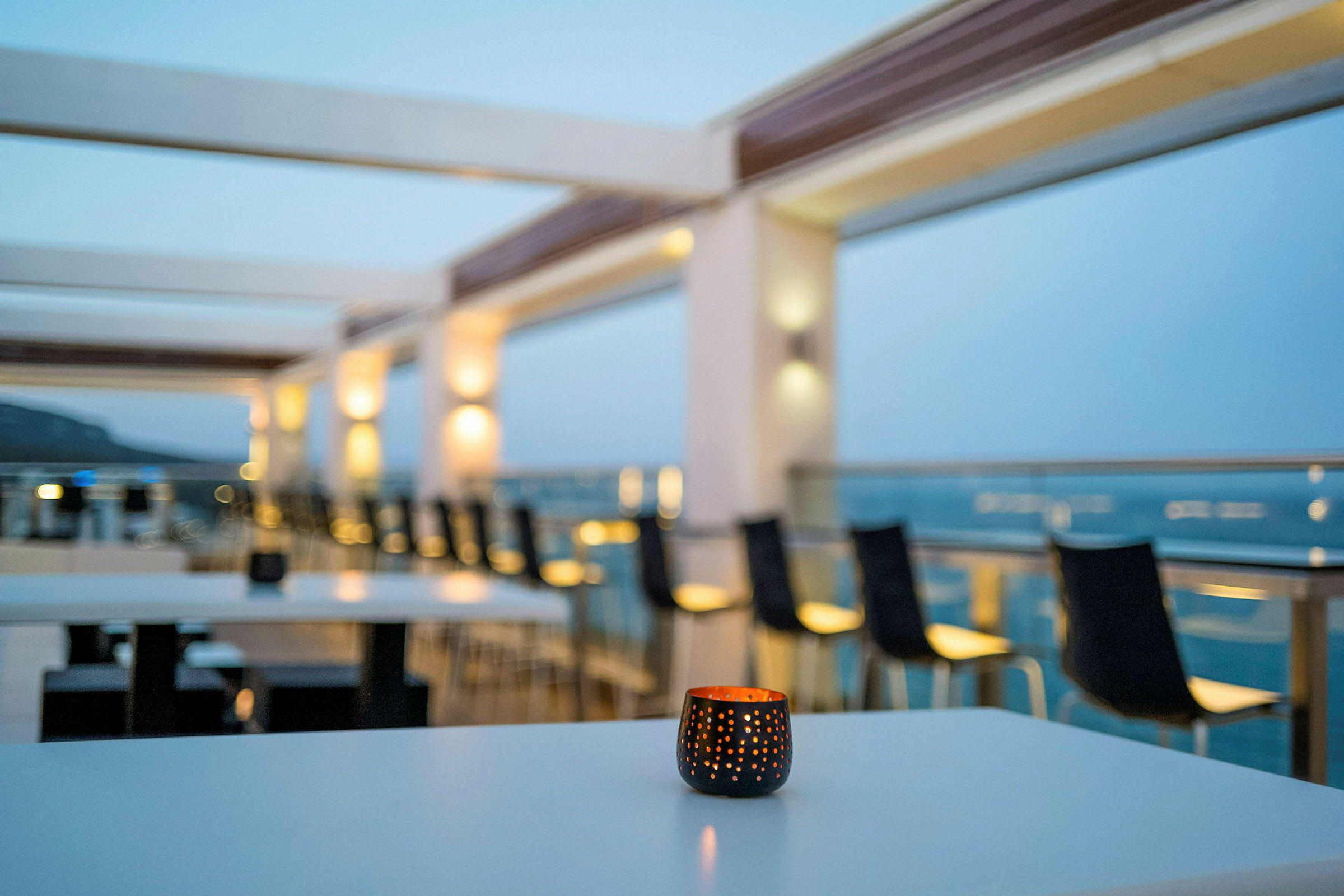 Utsikt över en terrass med bord och stolar, med ett ljus framme. (AI-genererad text)