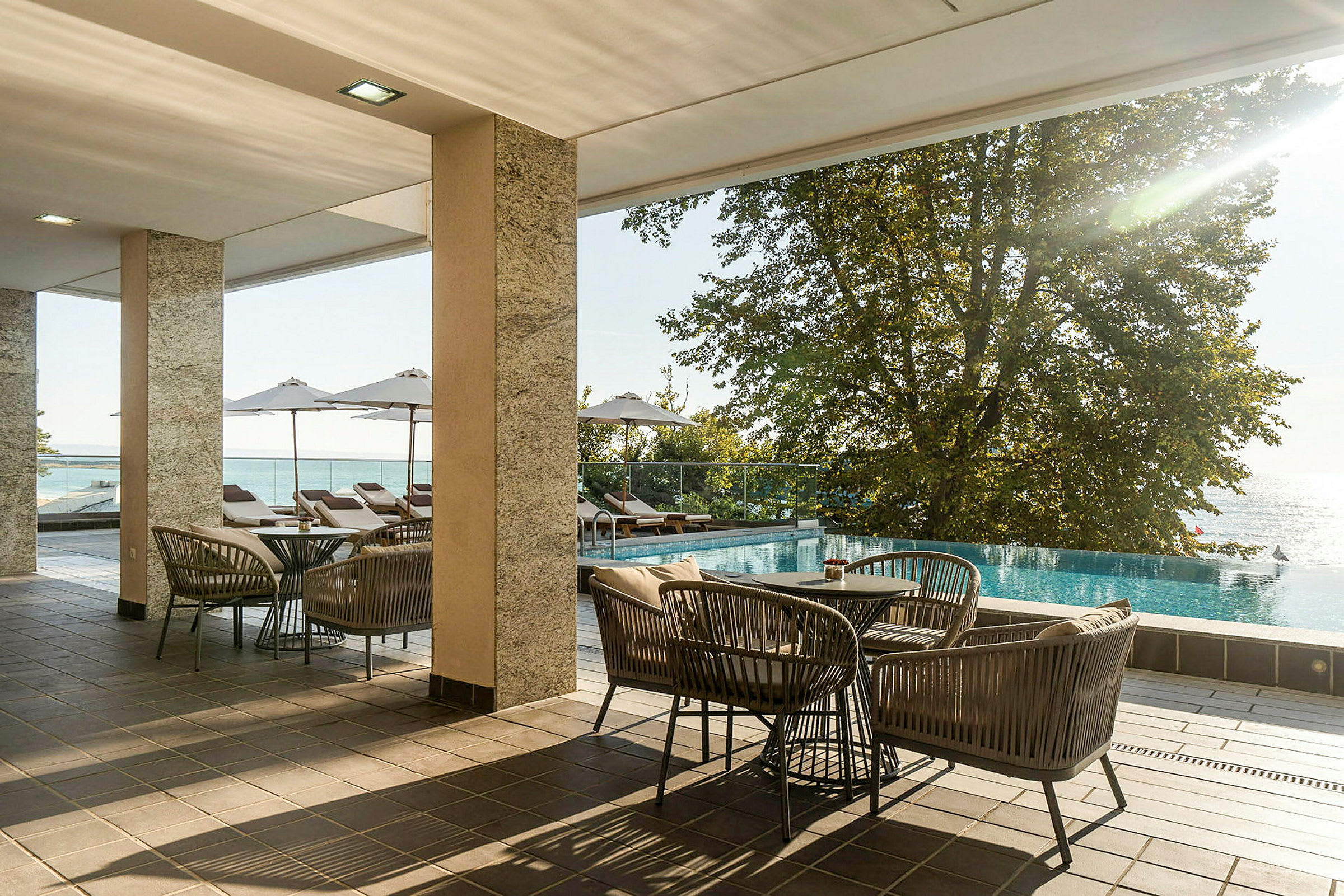 Möblerad terrass med utsikt över en pool och havet. (AI-genererad text)
