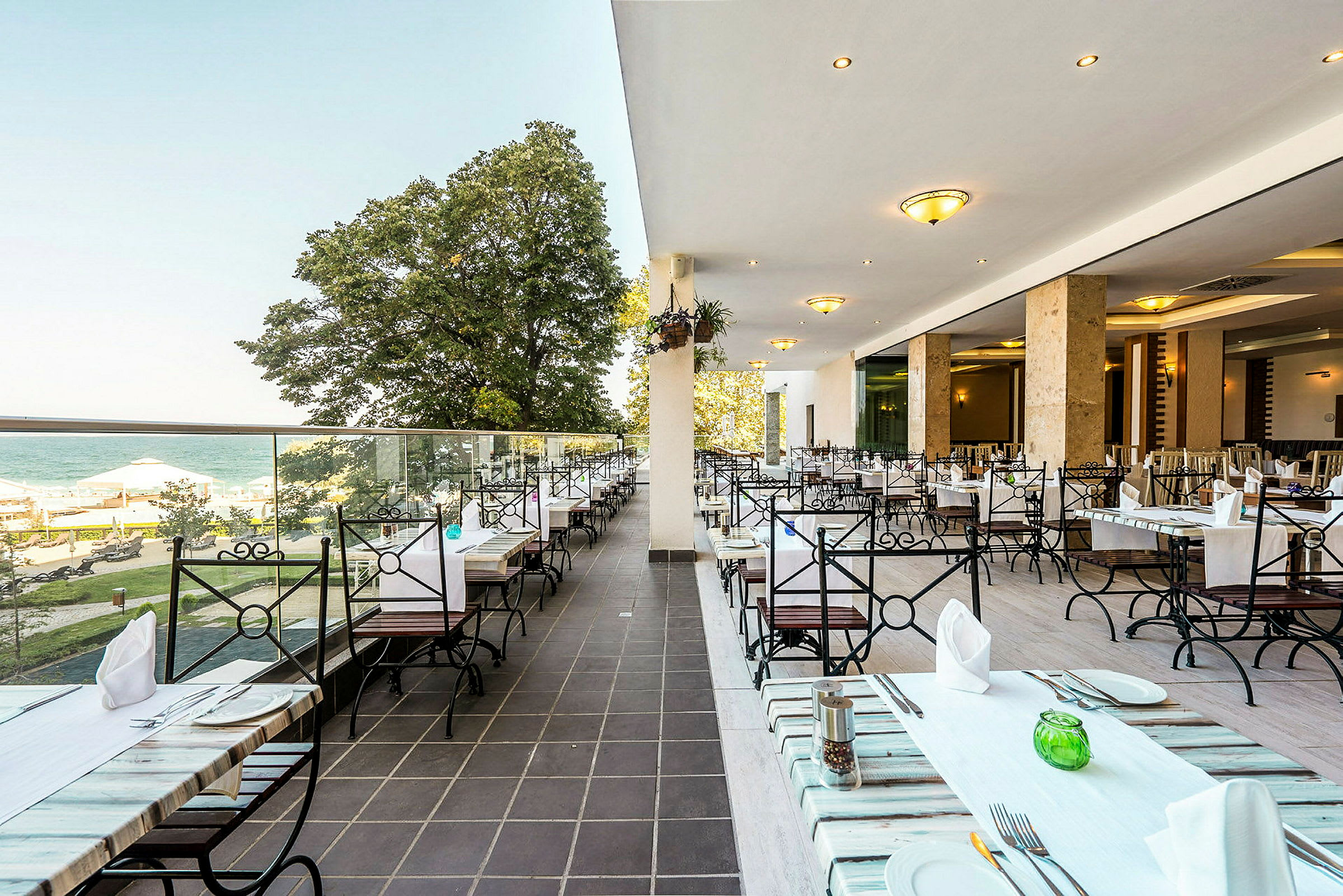 En öppen restaurangterrass med havsutsikt och sittplatser. (AI-genererad text)