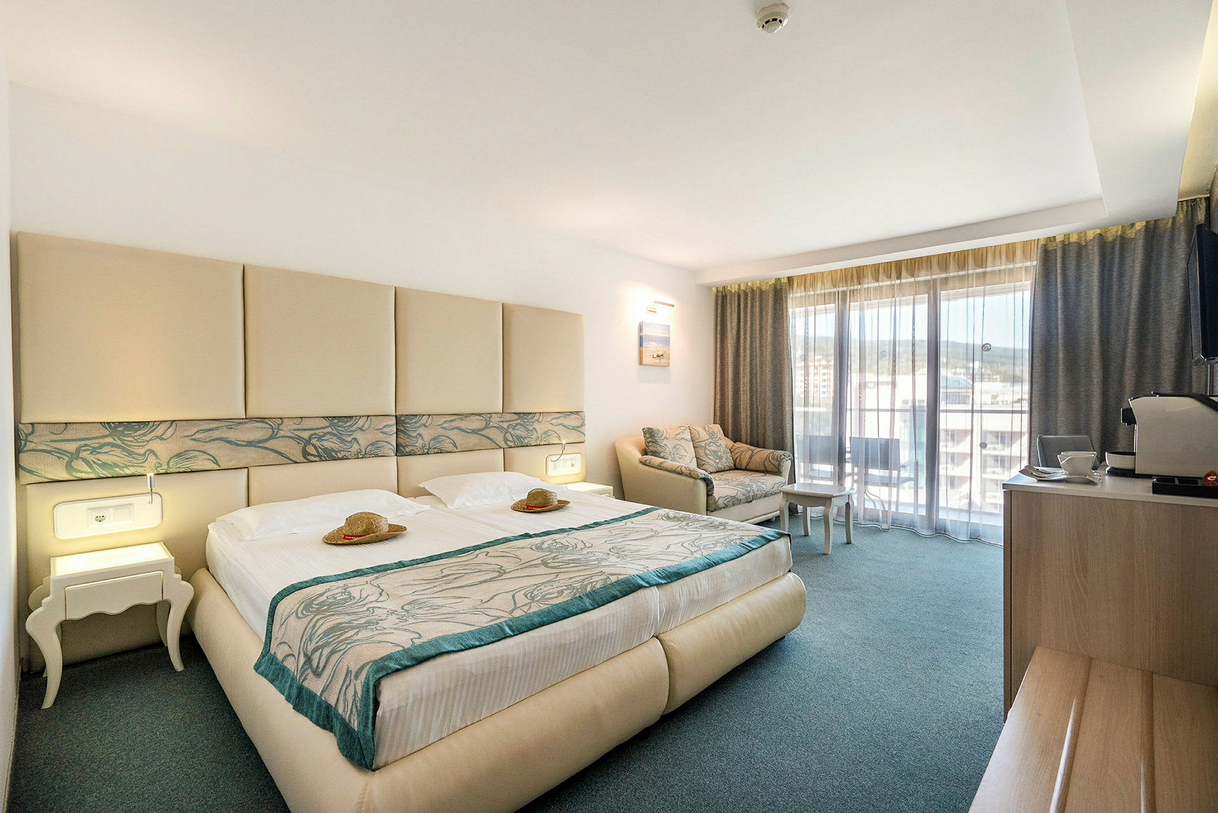 Hotellrum med dubbelsäng, soffa och balkong. (AI-genererad text)