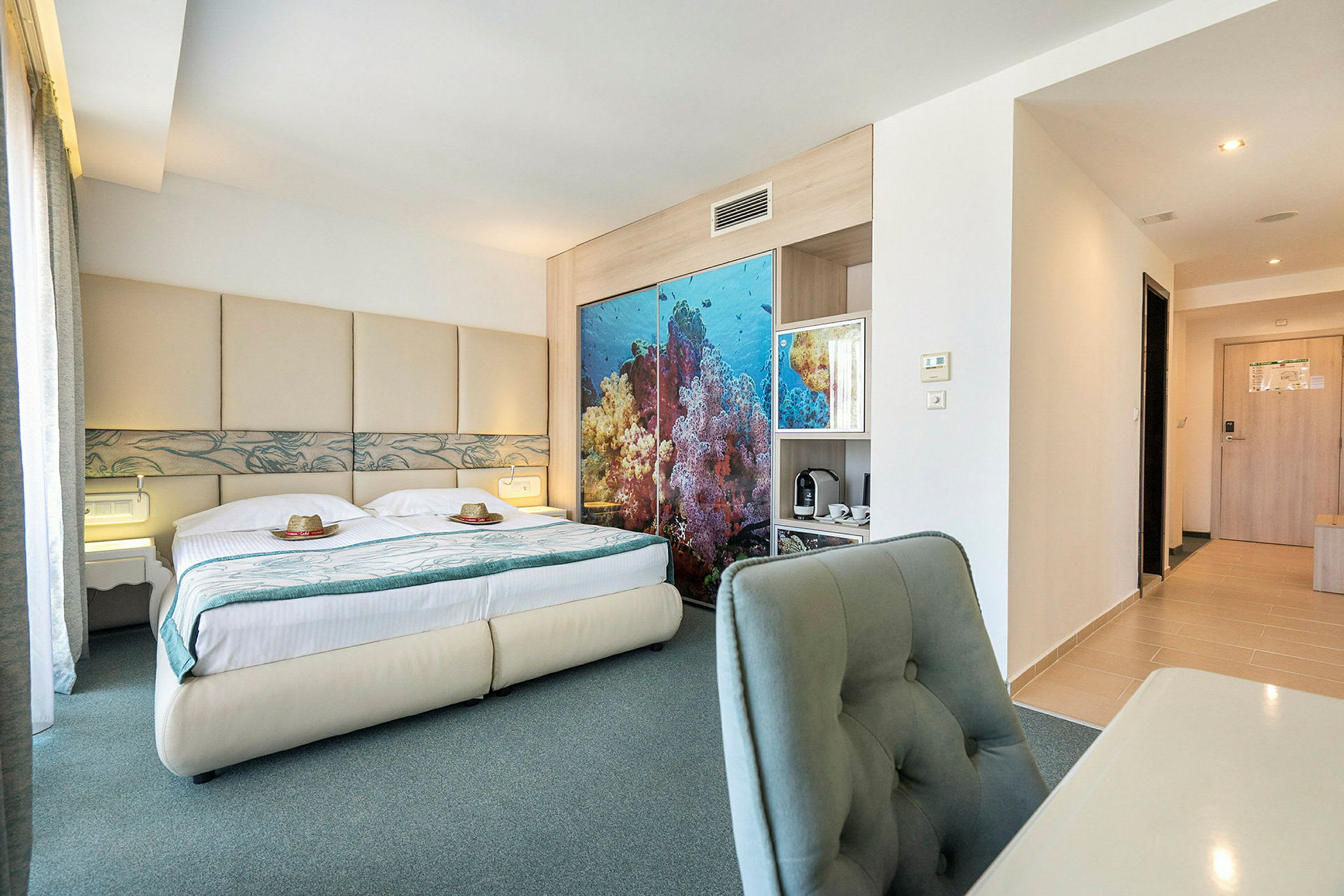 Bild av ett hotellrum med en dubbelsäng, havsinspirerat dekor bakom sängen och skrivbord med stol. (AI-genererad text)