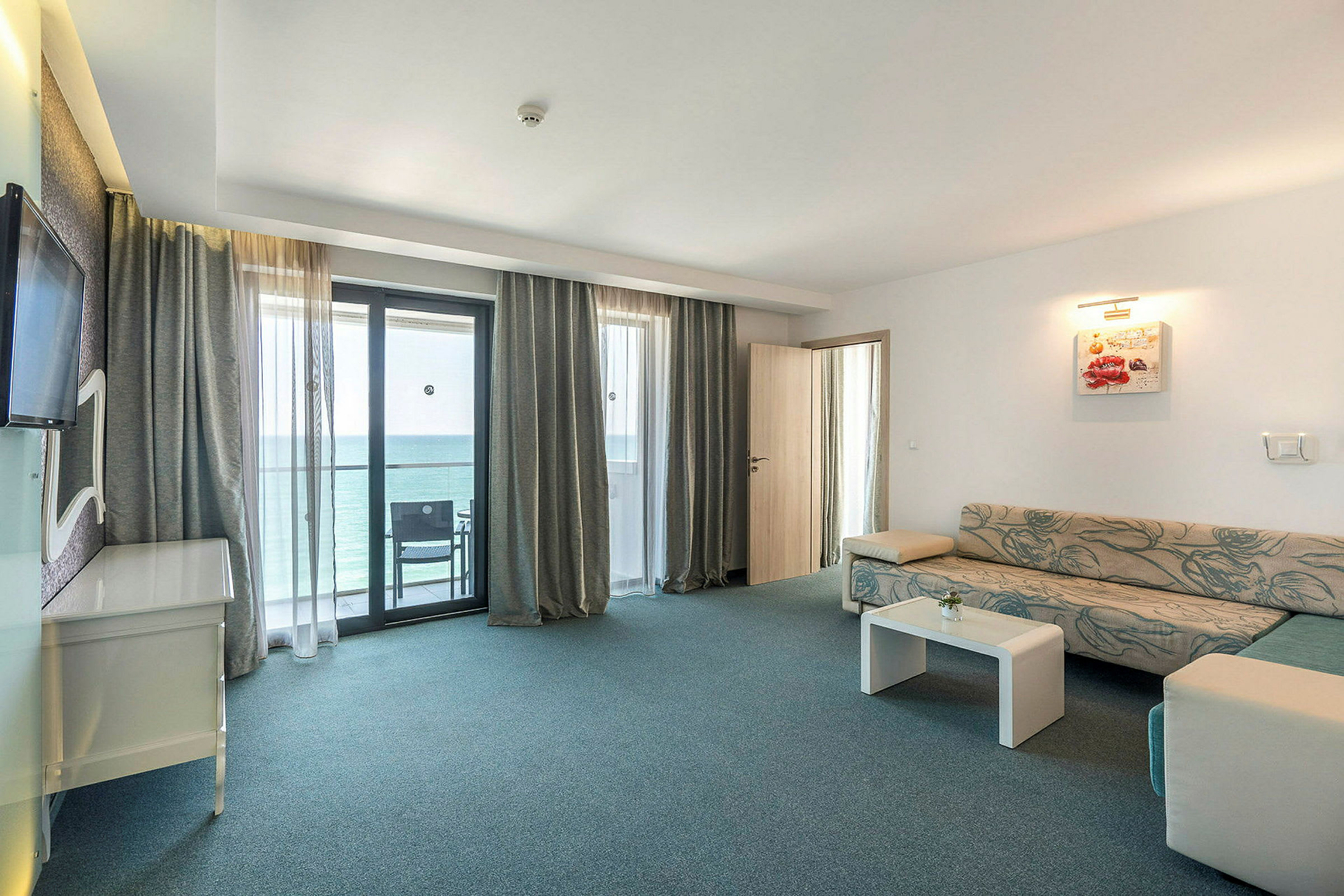 Ett hotellrum med sittgrupp och balkongutsikt. (AI-genererad text)