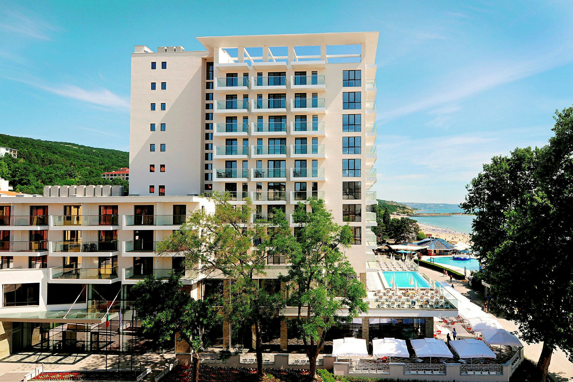 Bild på en modern hotellbyggnad med en pool i sitt område, belägen vid havet. (AI-genererad text)