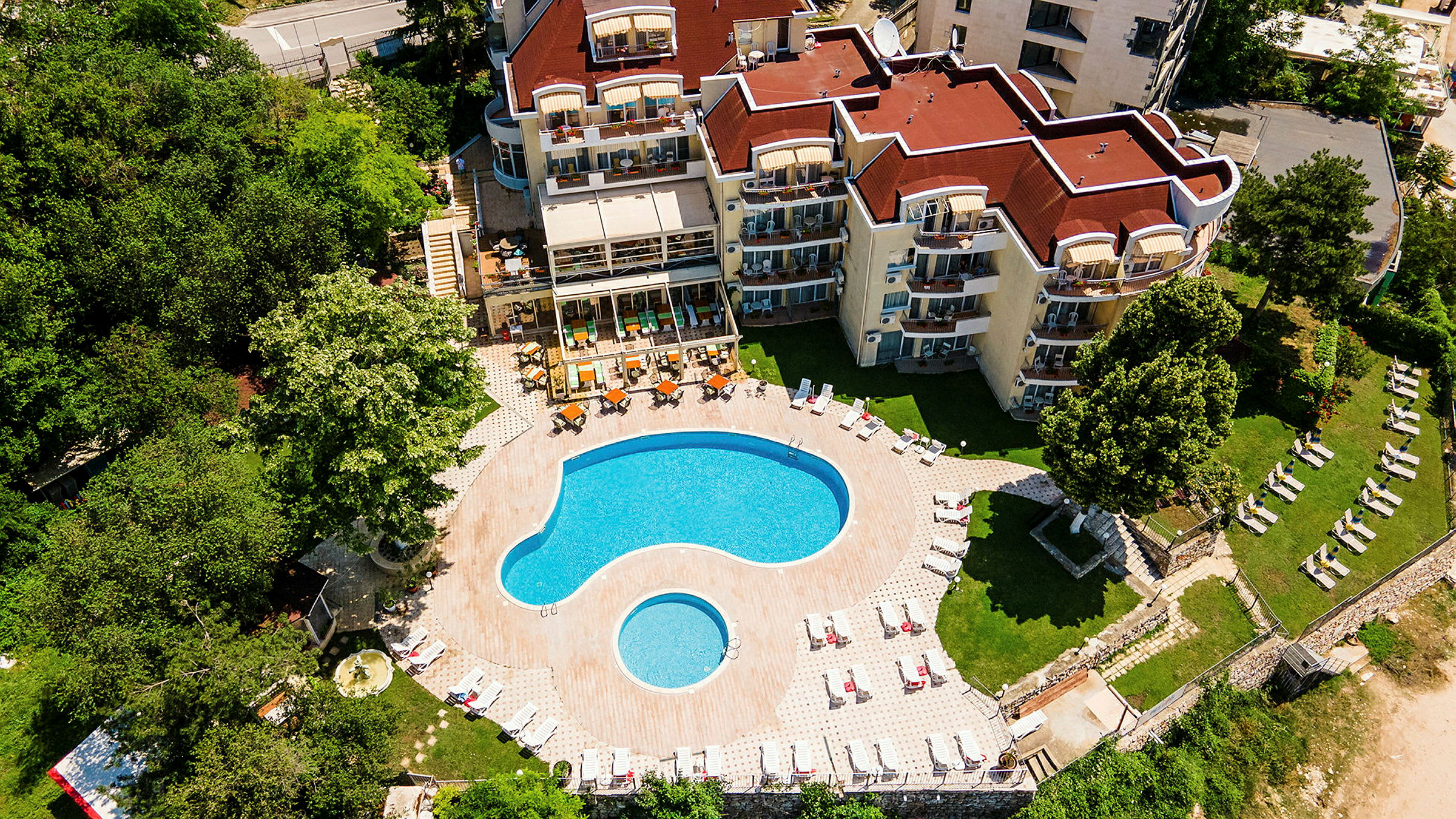Flygfoto av hotellkomplex med pool och omgivande grönska. (AI-genererad text)
