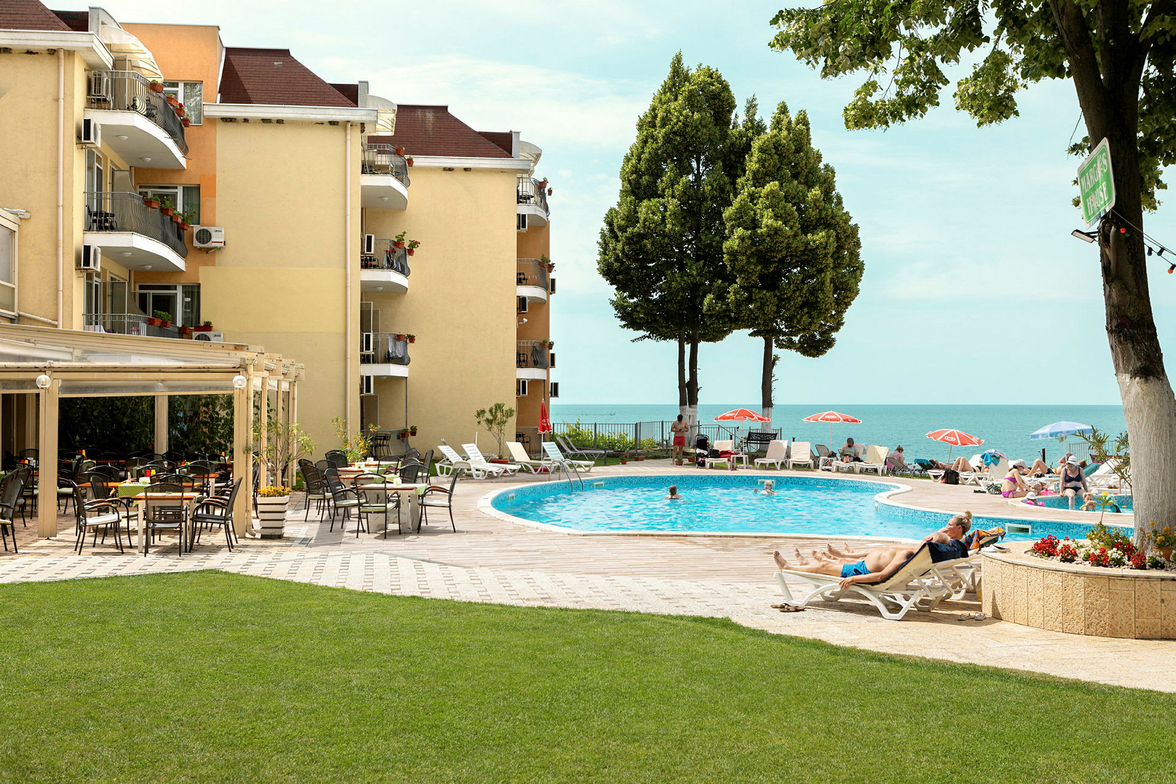 Poolområde vid hotell med solstolar, parasoller och utsikt mot havet. (AI-genererad text)