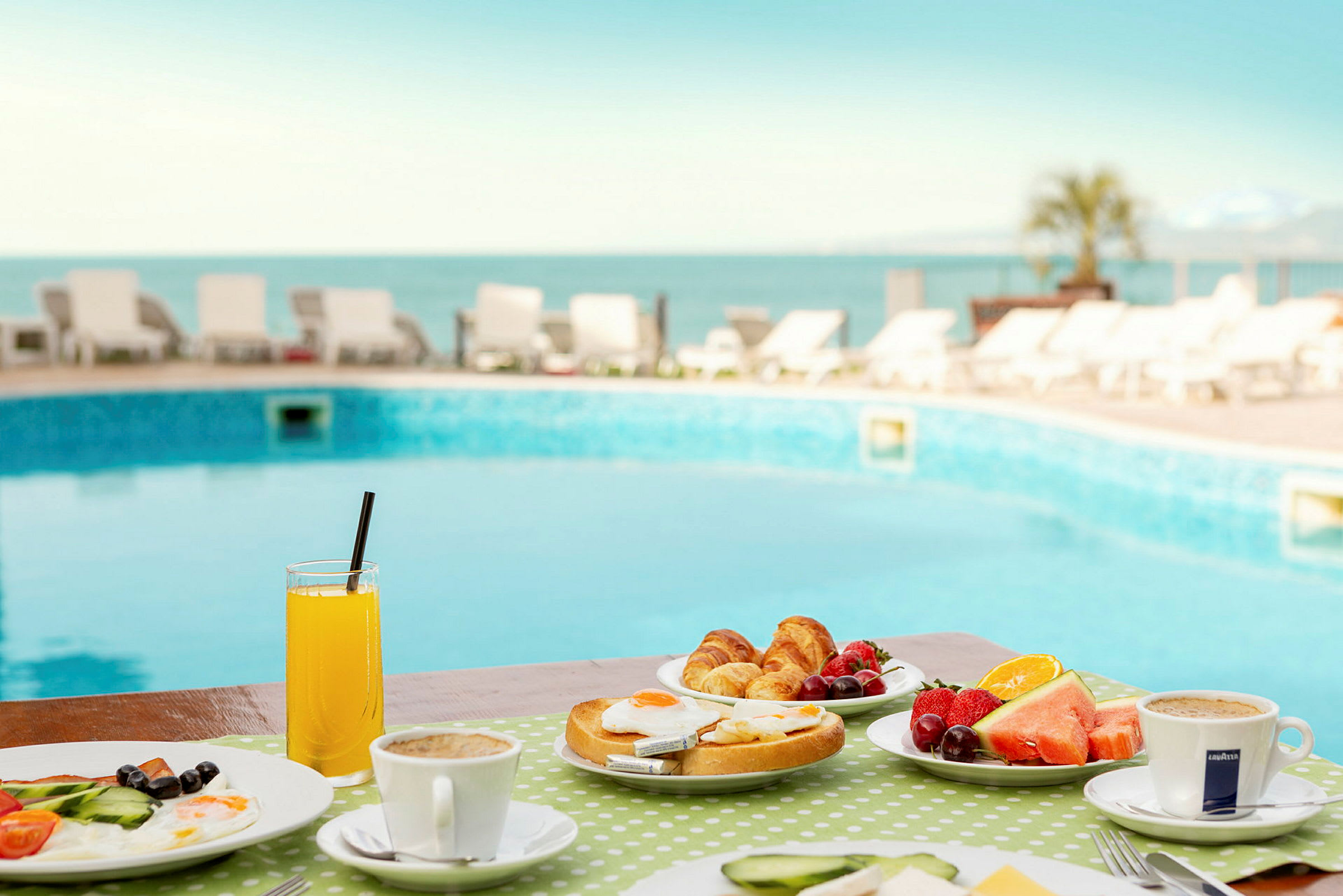 Frukost med bröd, frukt och kaffe vid en pool. (AI-genererad text)