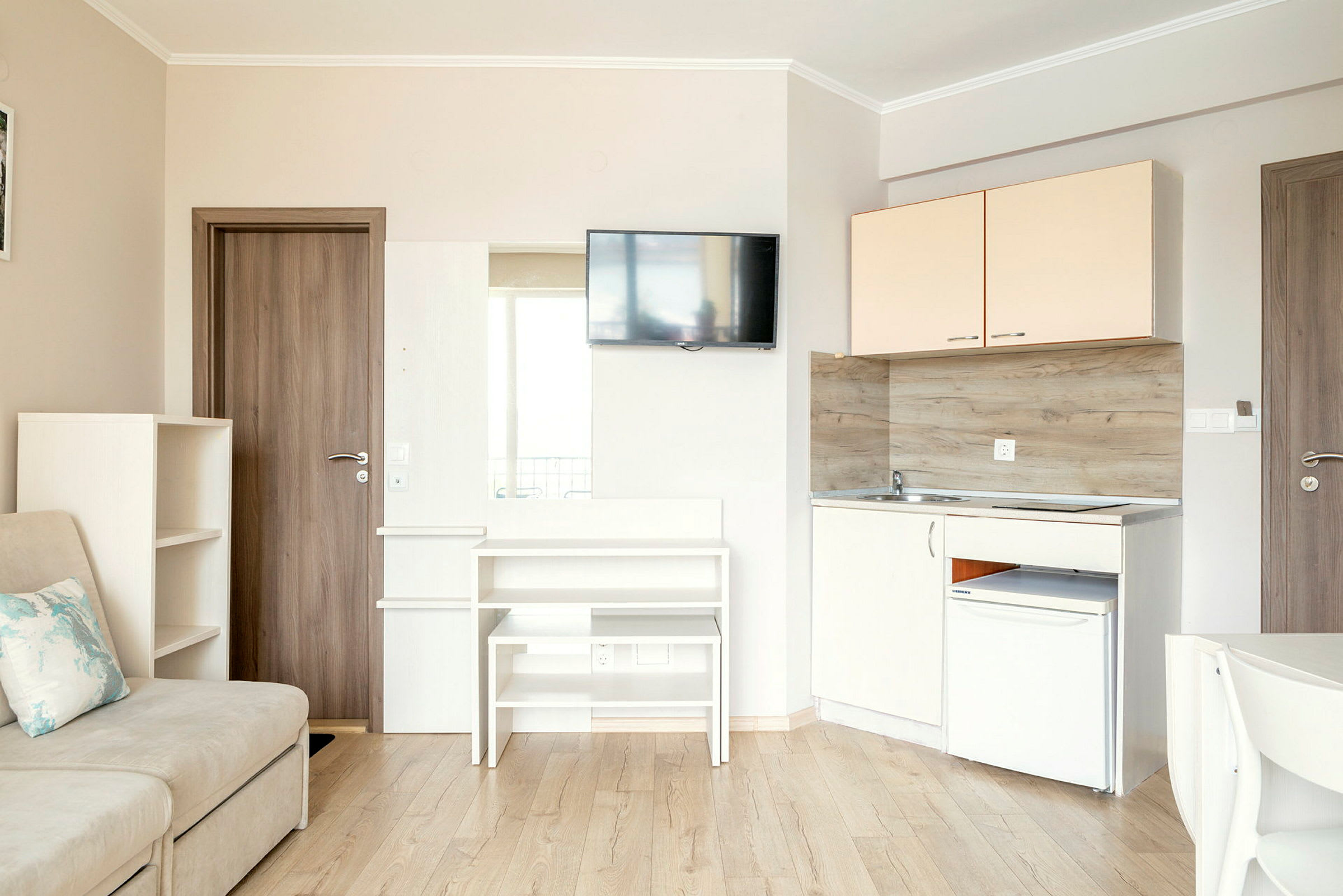 En liten kök och vardagsrumsdel med soffa, skåp, tv och köksutrustning. (AI-genererad text)