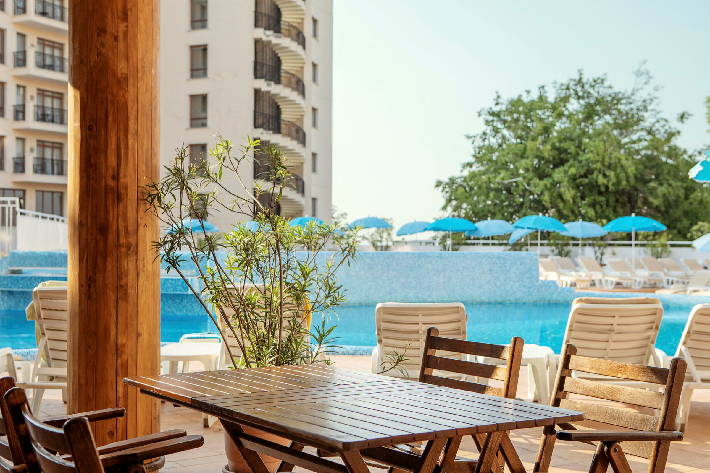 Bild av ett hotellområde med en pool, solstolar och parasoller. (AI-genererad text)