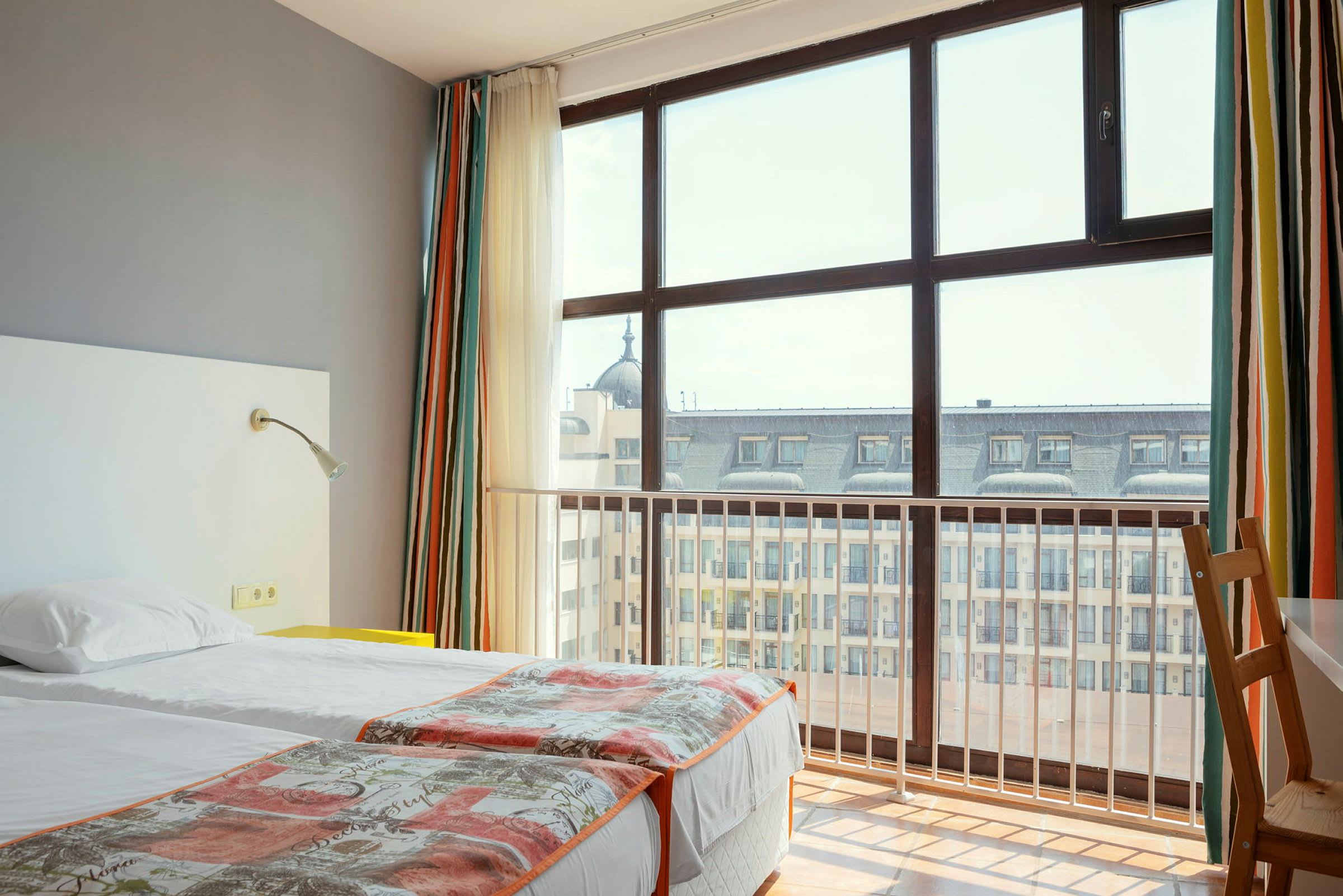 Hotellrum med två enkelsängar och stort fönster mot stadsvy. (AI-genererad text)