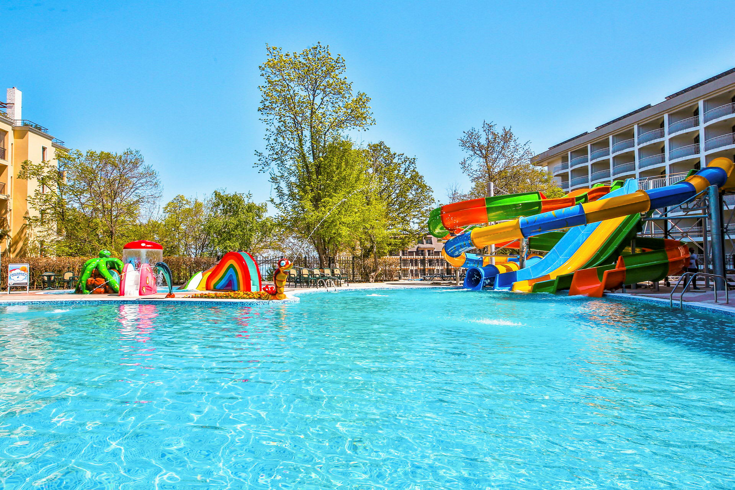 Utomhuspool med vattenrutschbanor och färgglad lekutrustning för barn. (AI-genererad text)