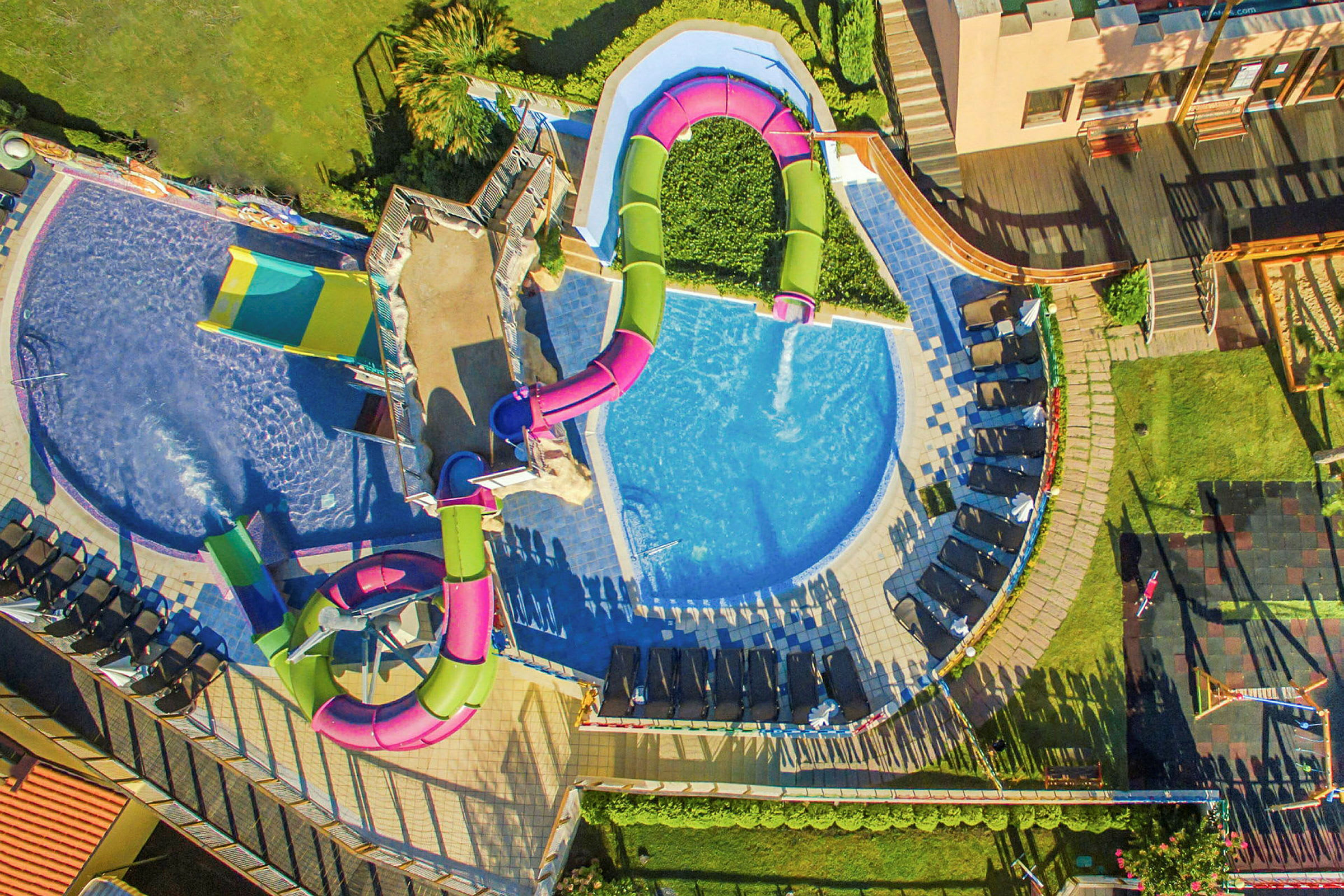 Färgglada vattenrutschbanor och pool fotograferade ovanifrån. (AI-genererad text)