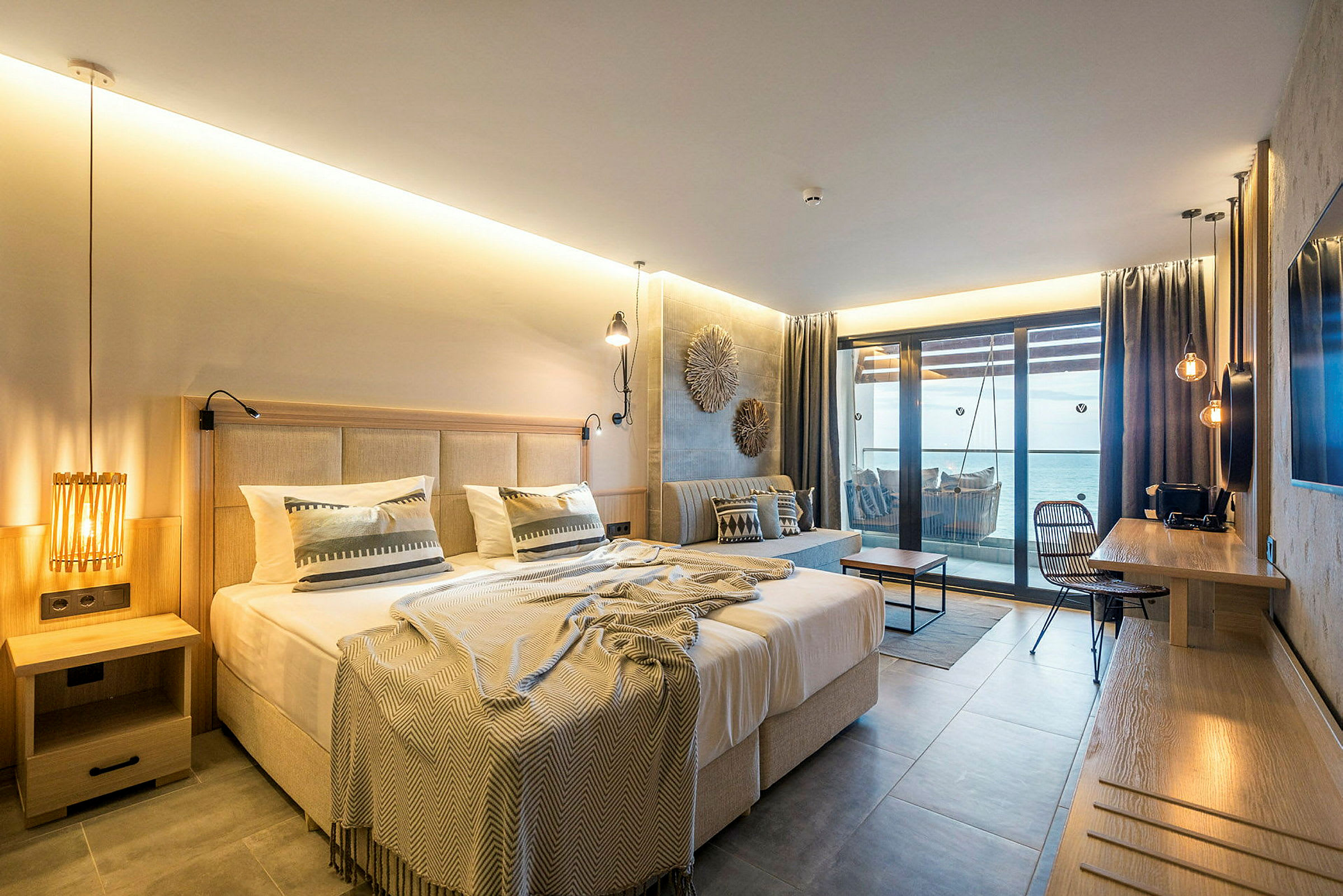 Rum med en dubbelsäng, soffa, skrivbord och balkong med havsutsikt. (AI-genererad text)