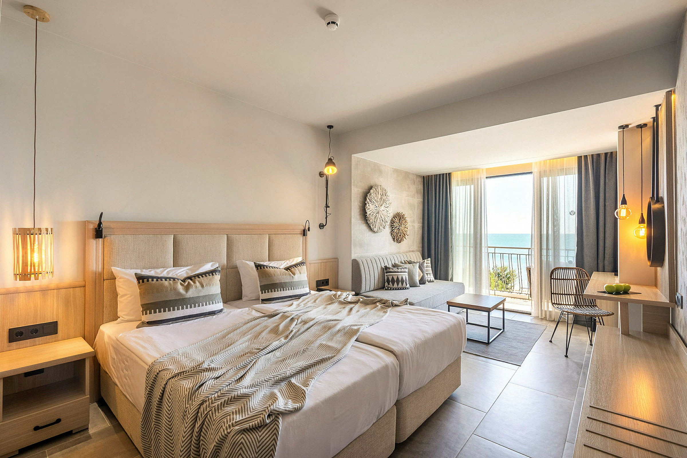Hotellrum med dubbelsäng, sittplats och balkong med utsikt över havet. (AI-genererad text)