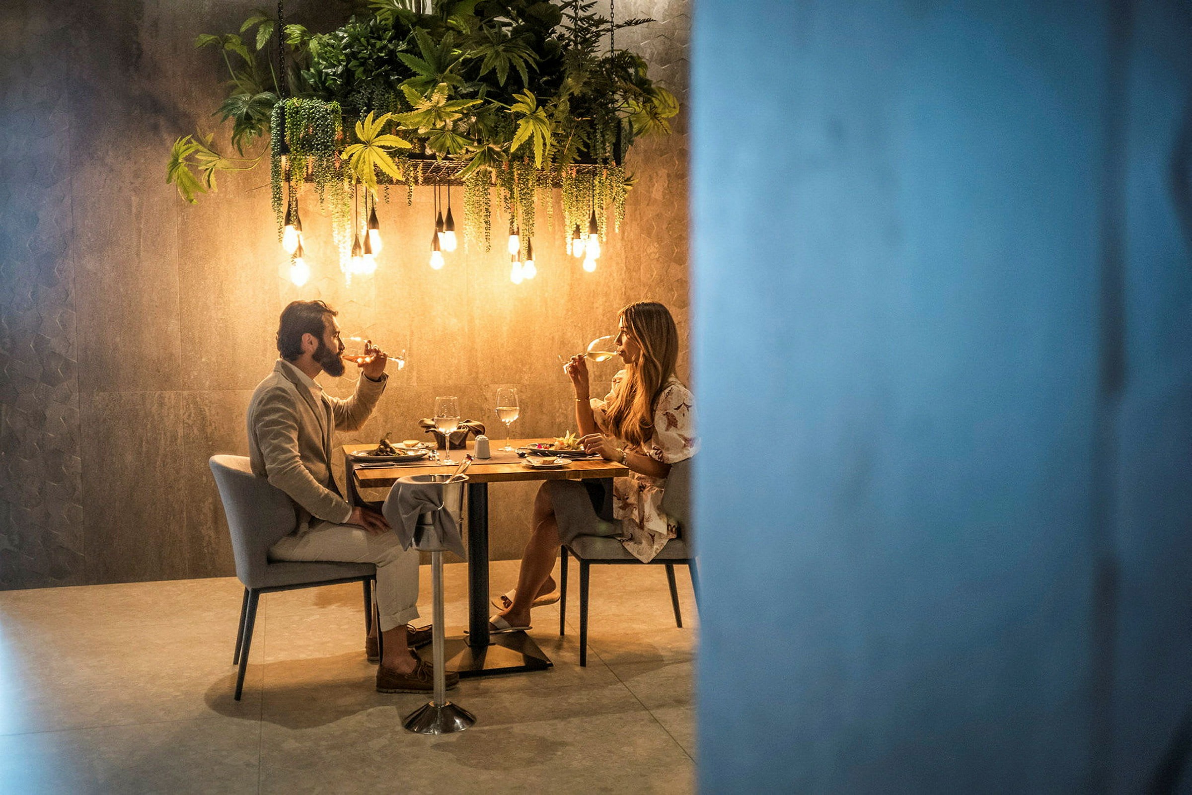 Två personer sitter vid ett dukat bord och äter middag i en elegant miljö. (AI-genererad text)