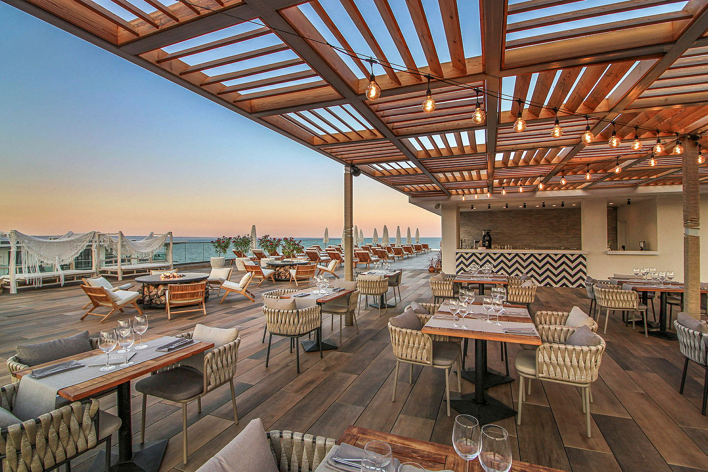 Restaurang med terrass och havsutsikt under träpergola. (AI-genererad text)