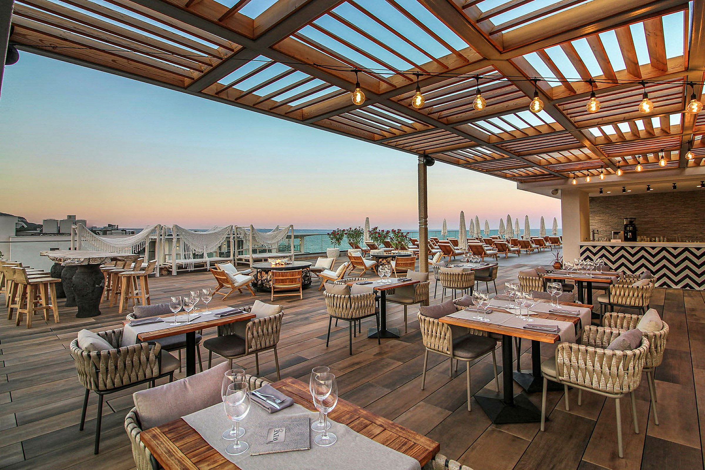Terrass med utomhusrestaurang och liggstolar under träpergola. (AI-genererad text)