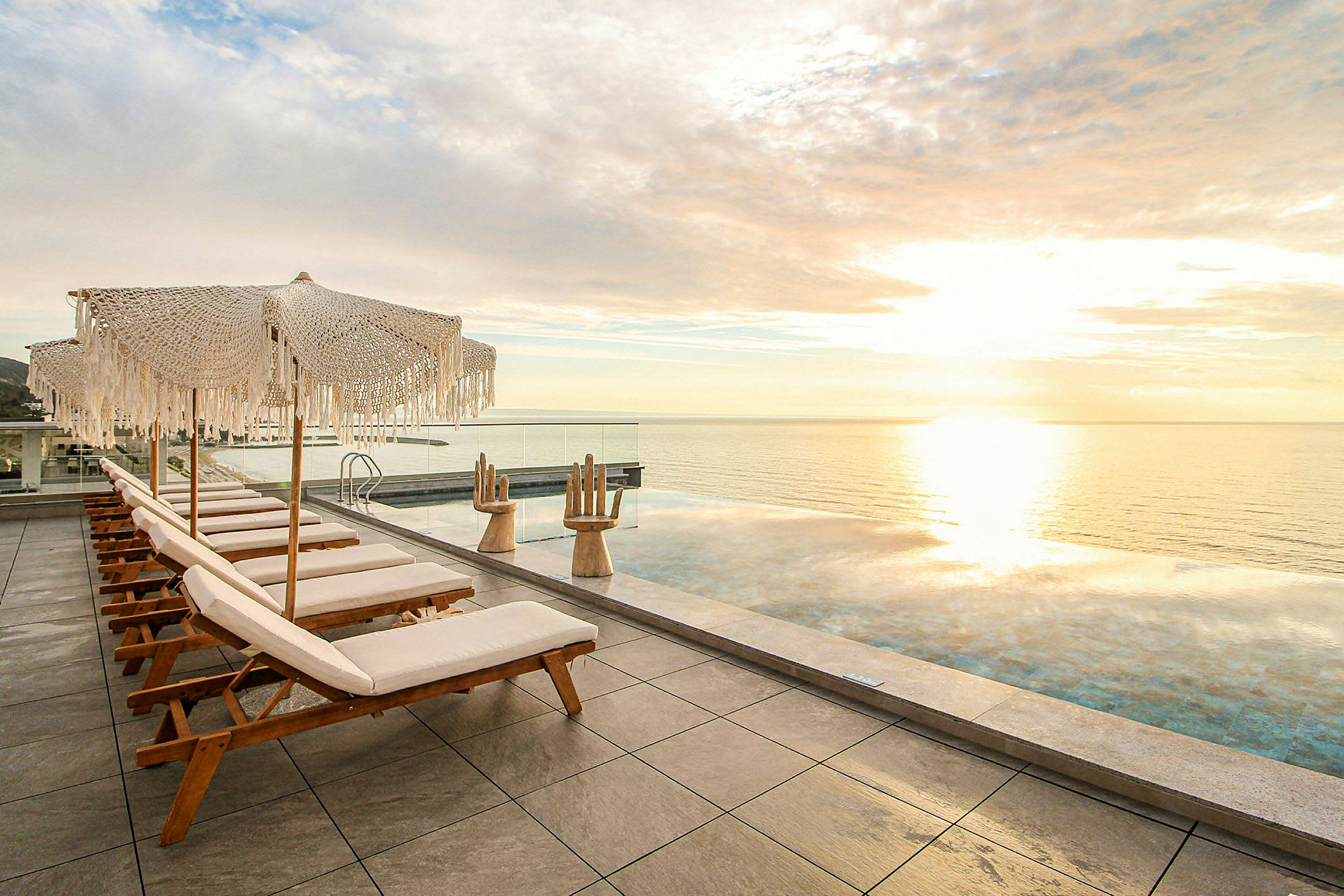 Solstolar och parasoller vid en infinitypool med utsikt över havet. (AI-genererad text)