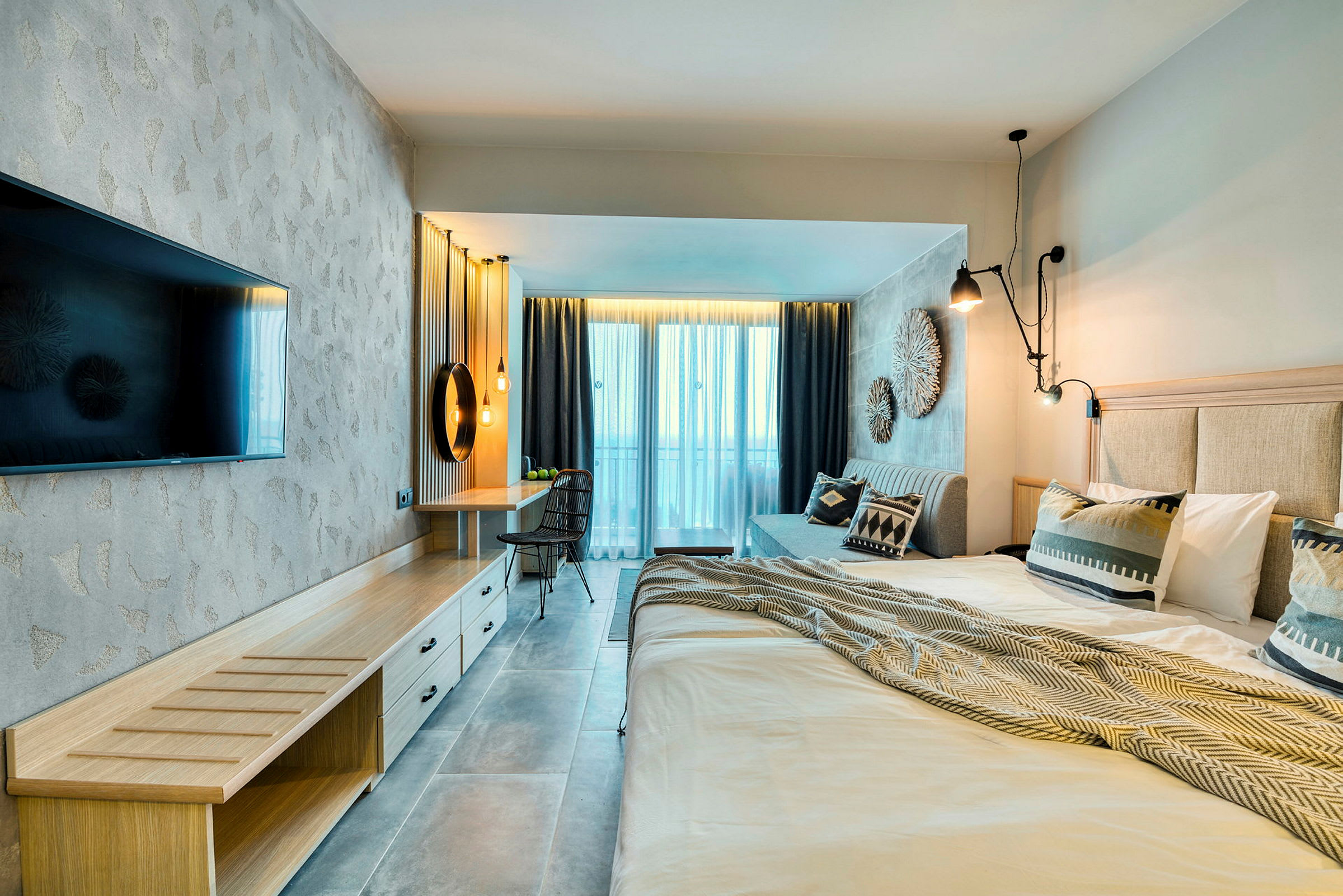 Modernt hotellrum med dubbelsäng, TV, skrivbord och balkong. (AI-genererad text)