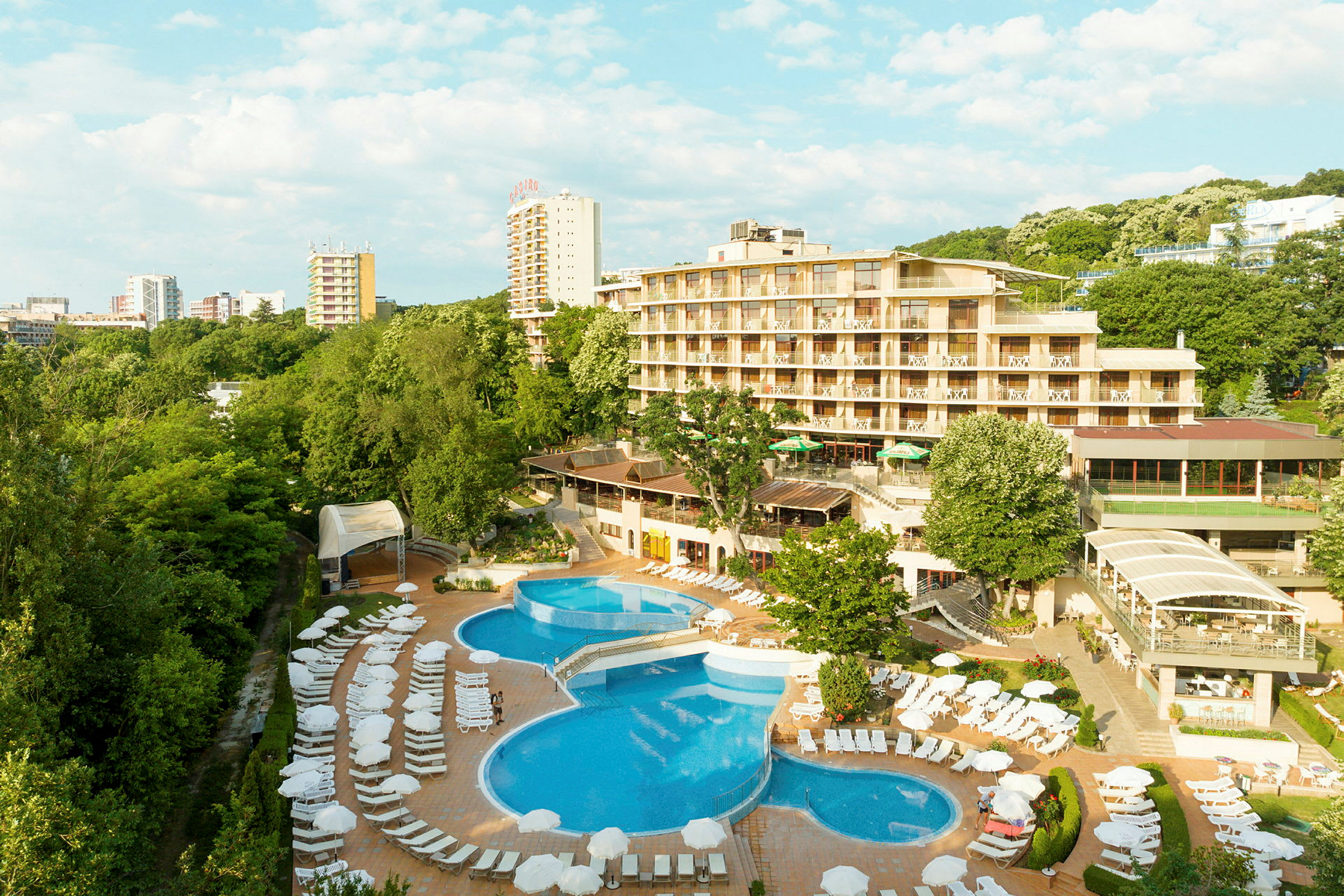 Ett hotell med pool och solstolar, omgiven av grönska. (AI-genererad text)