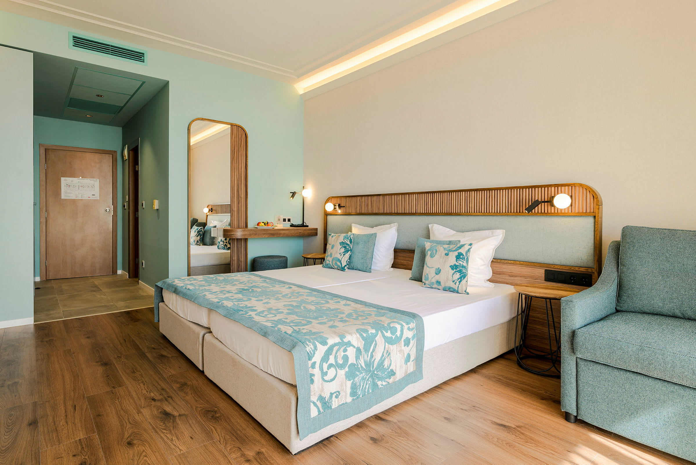 Ett hotellrum med en dubbelsäng, en fåtölj och ett skrivbord. (AI-genererad text)