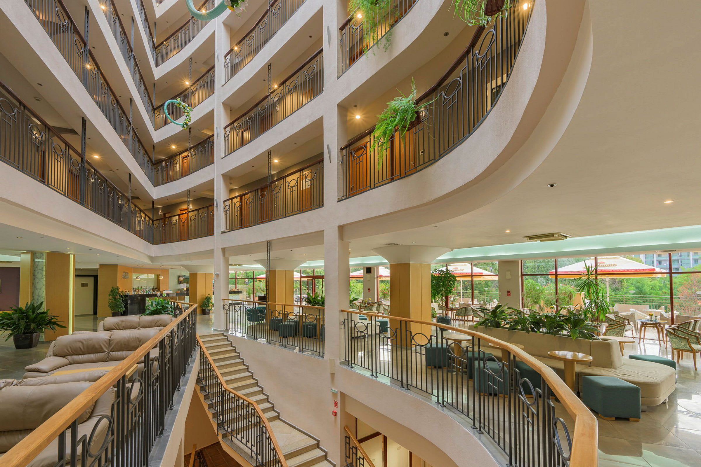 Interiör av ett hotell med flerplanigt atrium, sittgrupper och växter. (AI-genererad text)