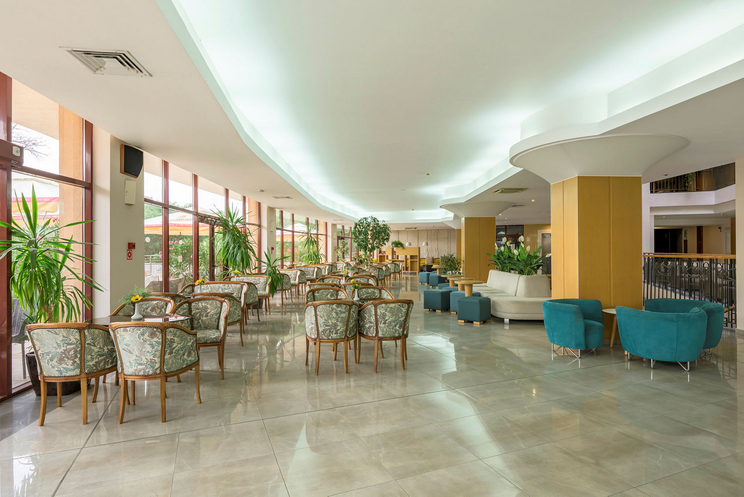 Hotellobby med bord och stolar samt gröna växter. (AI-genererad text)