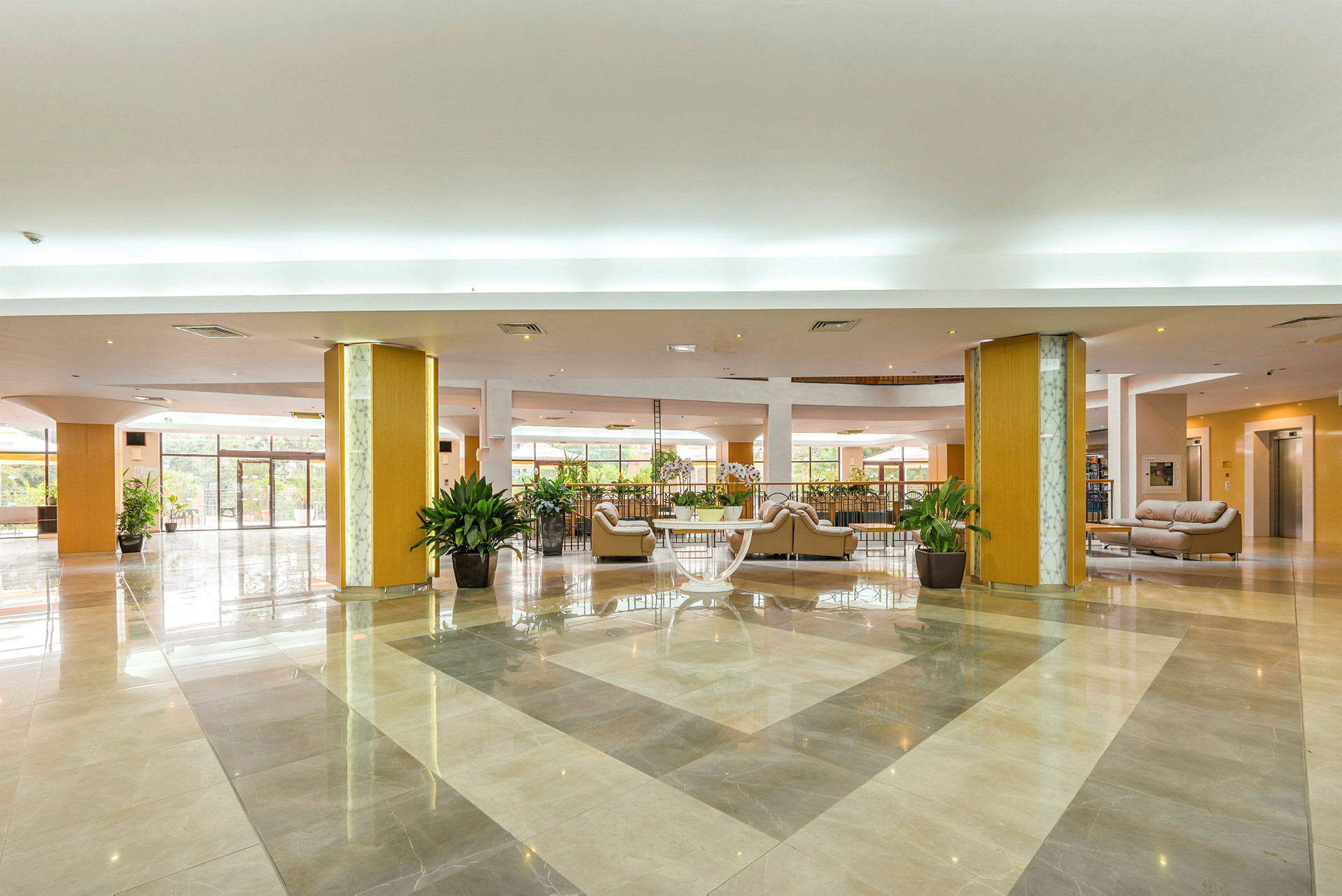 Ett rymligt hotellobbyutrymme med sittmöbler och växter. (AI-genererad text)